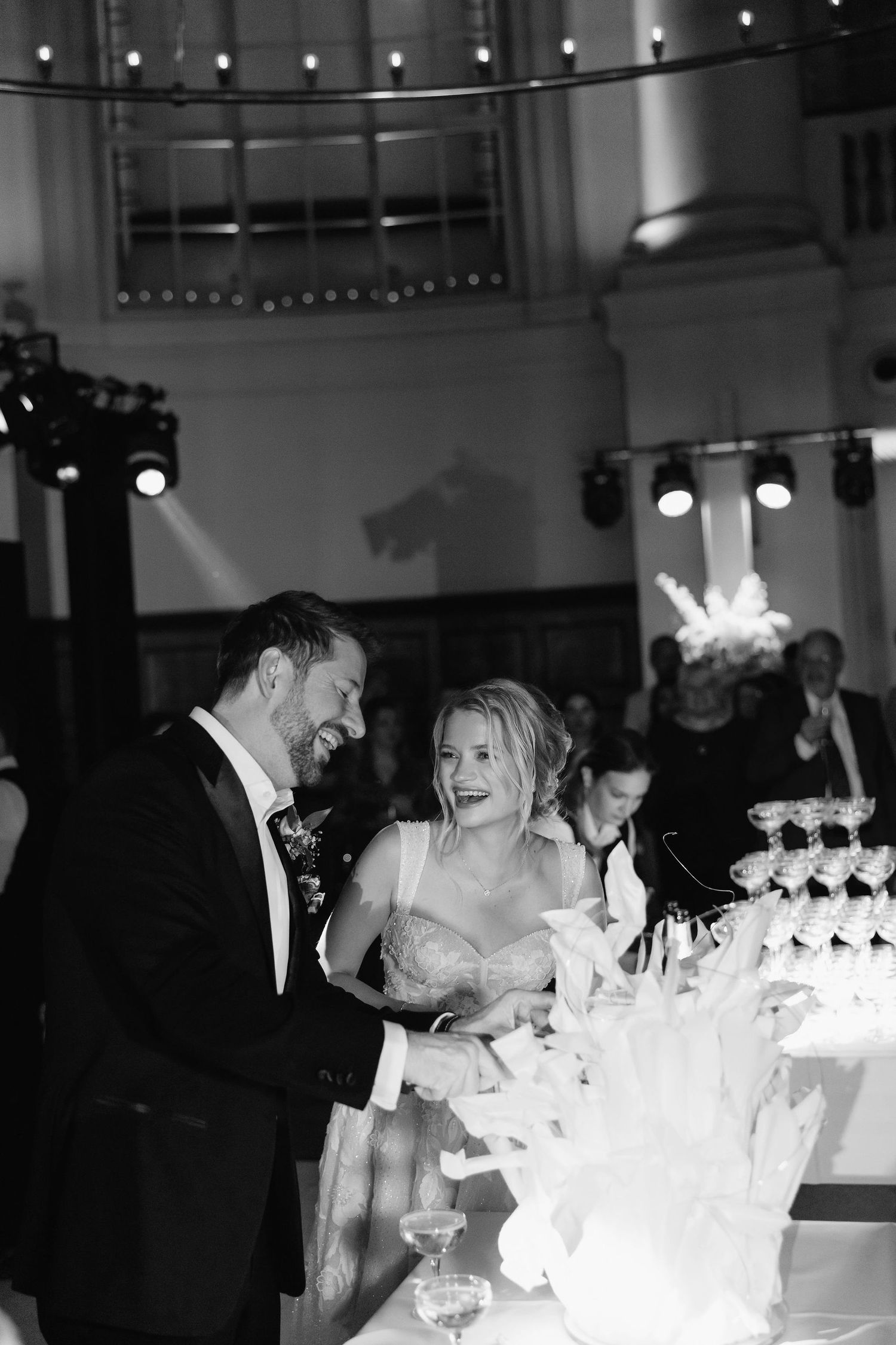 Newlyweds share an intimate moment beside their illuminated wedding cake display.