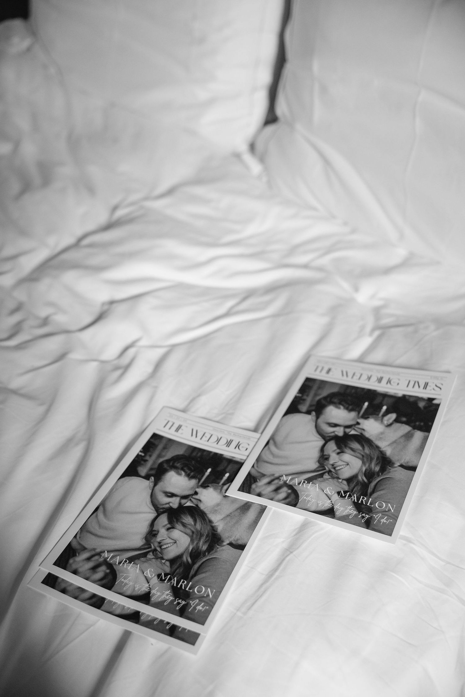 Black and white photo of magazines scattered on white bedsheets.