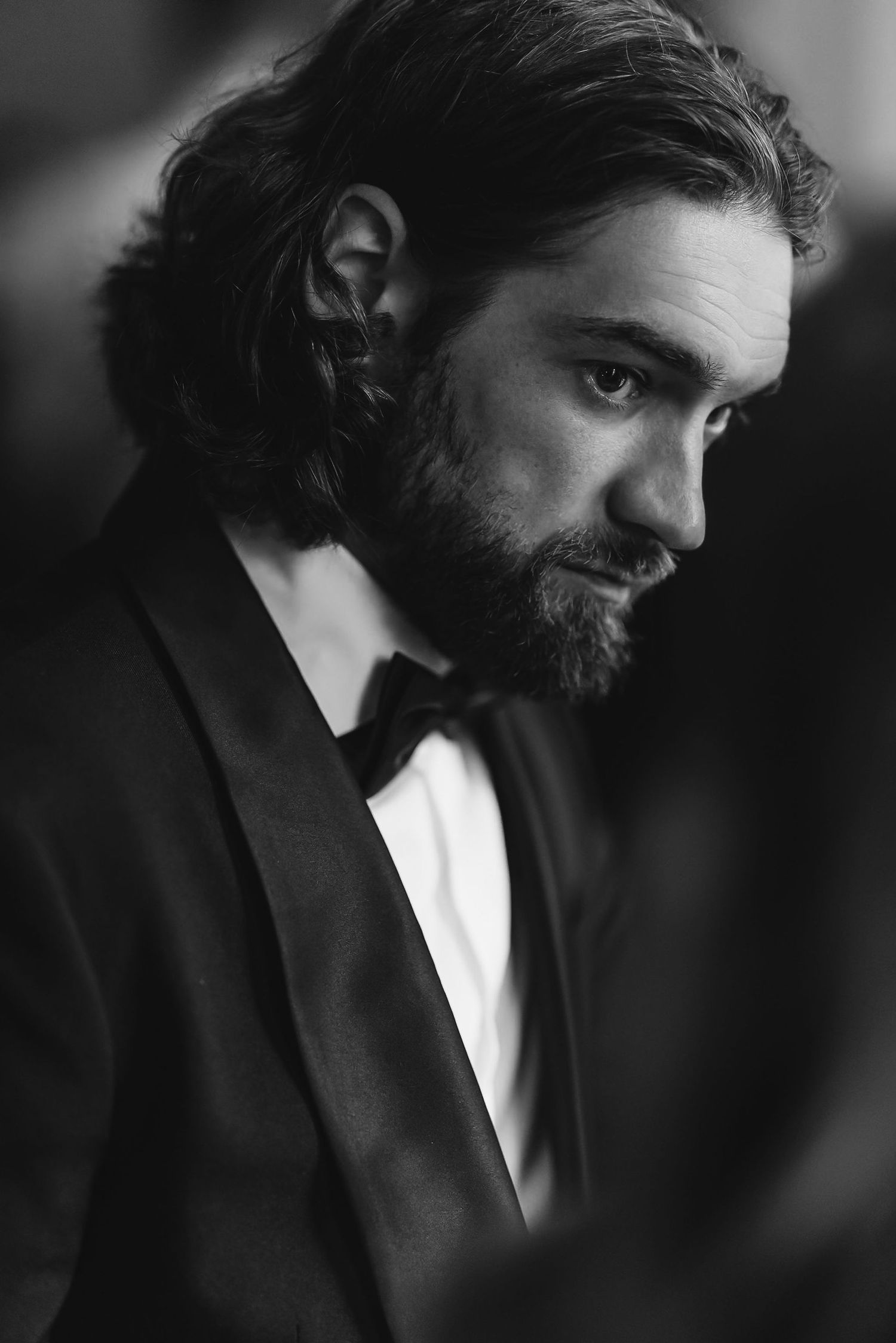 Dramatic black and white portrait of man in tuxedo with beard.