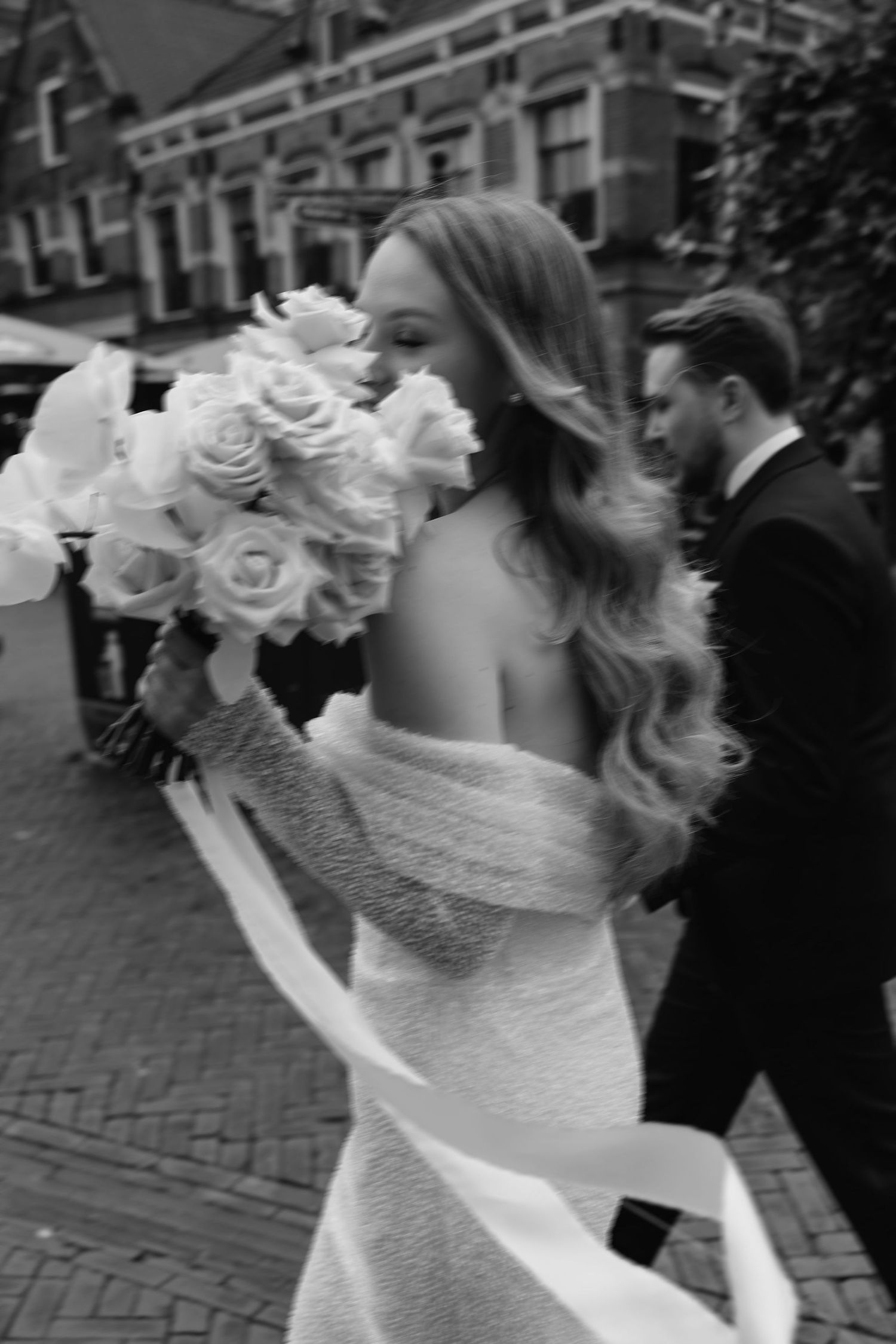 Black and white sequence showing bride twirling in lace dress with floral crown against brick building.
