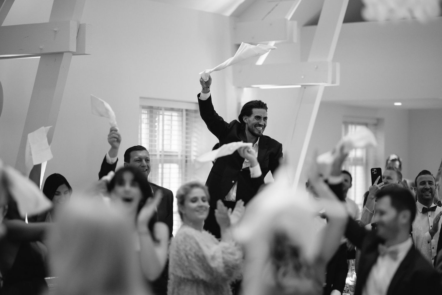 Black and white photo of celebration with people waving papers in the air.