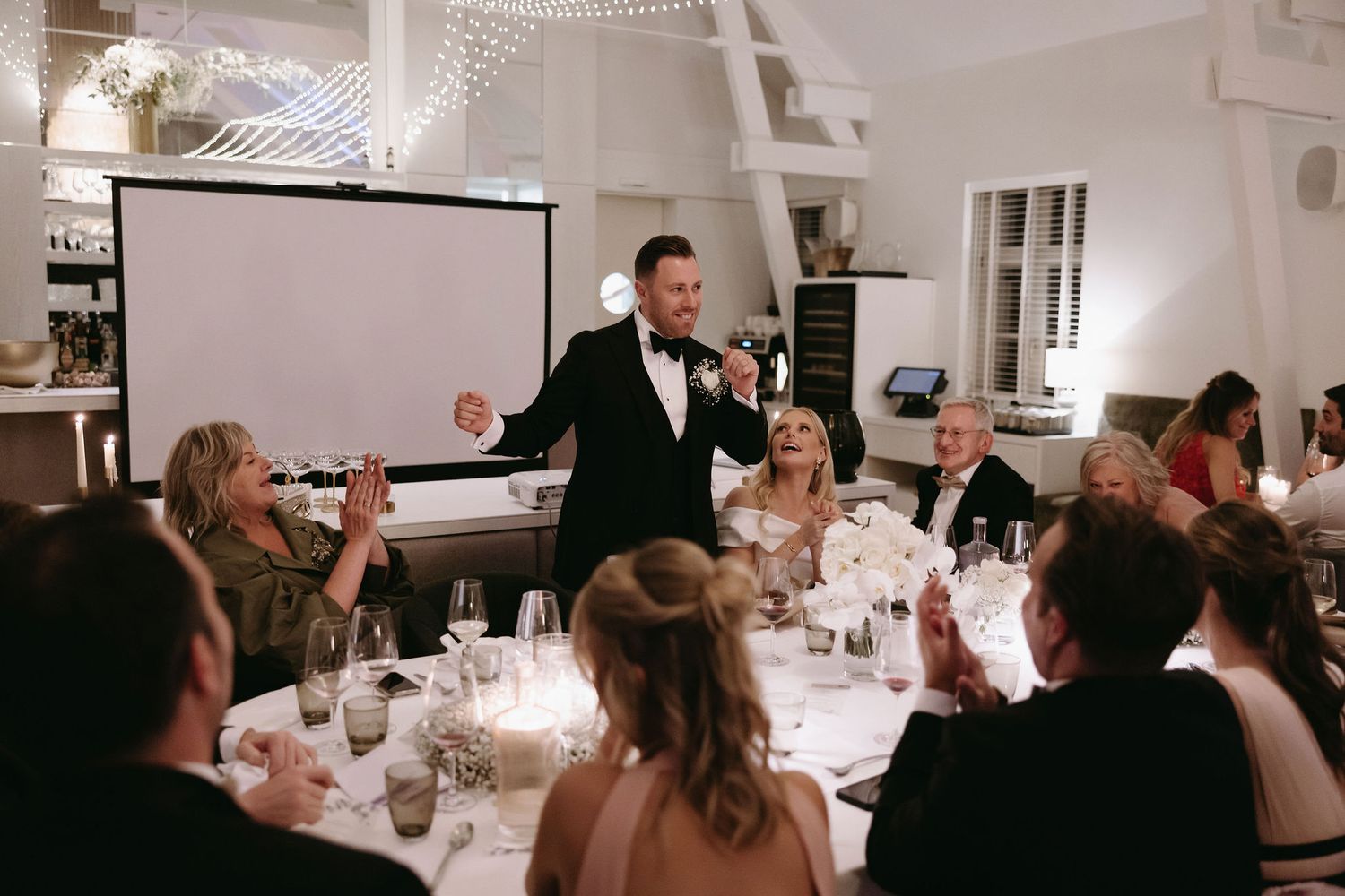 Wedding reception dinner scene with tables of guests celebrating indoors.