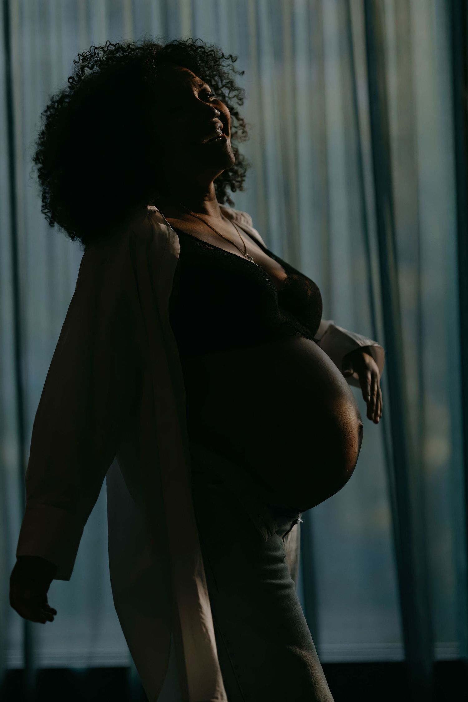 Silhouette of woman against window backlight in intimate lifestyle photoshoot.