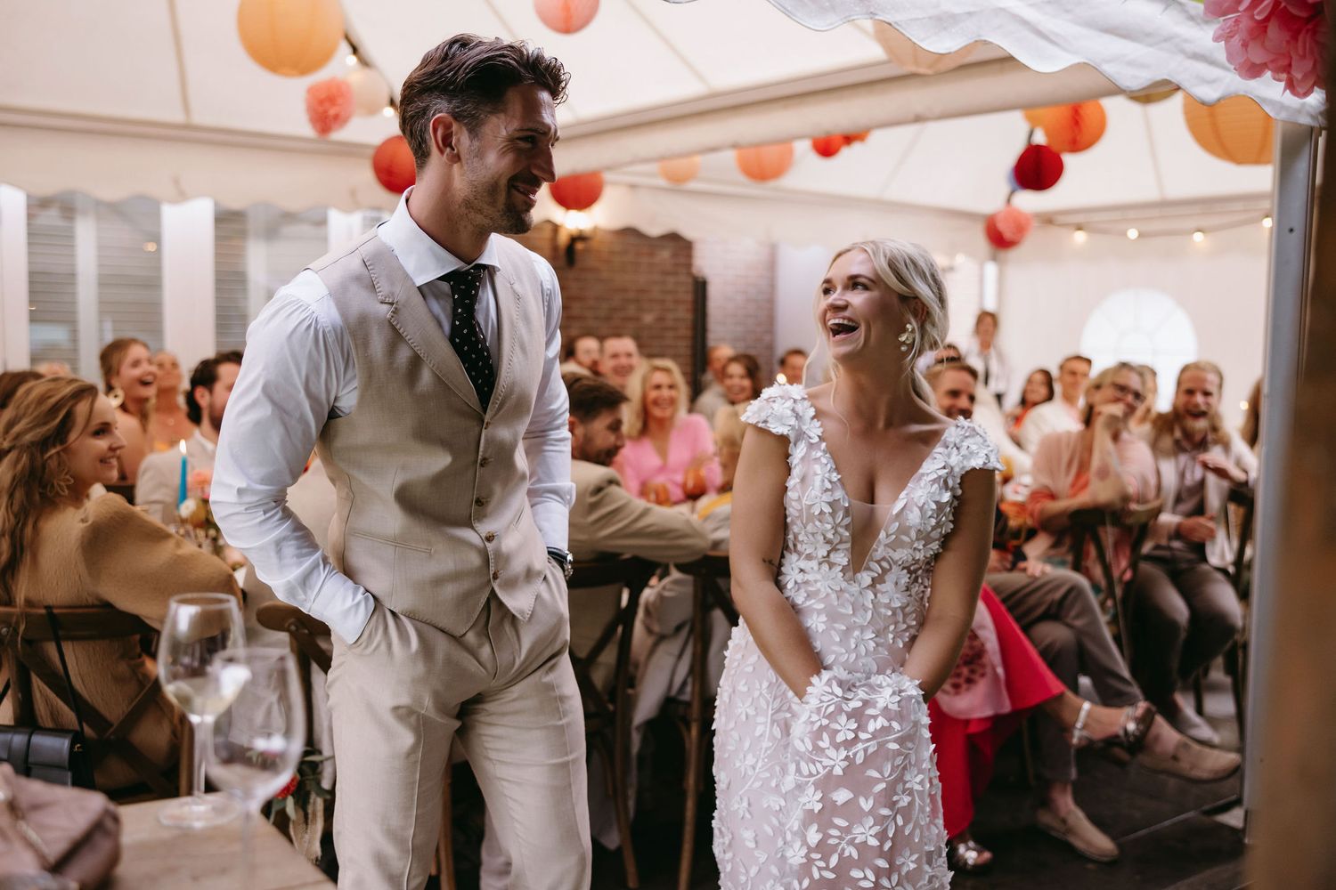Couple dancing at wedding reception under festive orange and white lantern decorations.