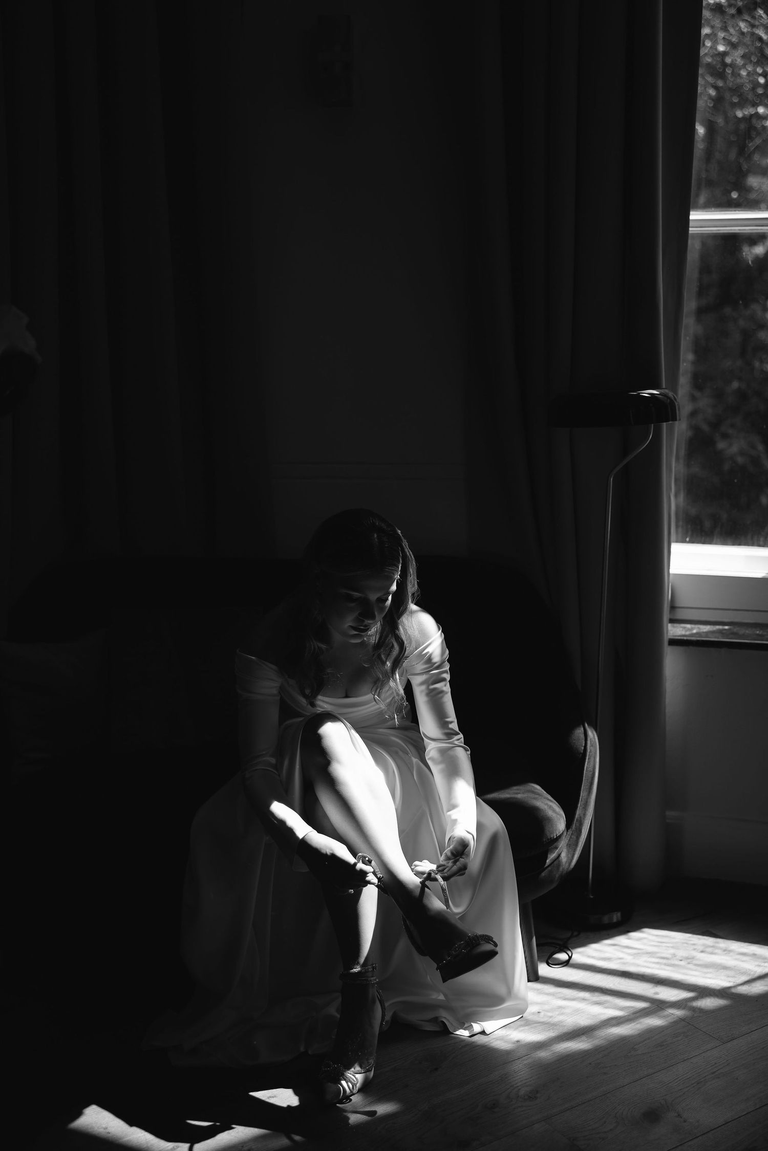 A black and white scene of a person working at a sunlit desk with dramatic shadows cast through a window.