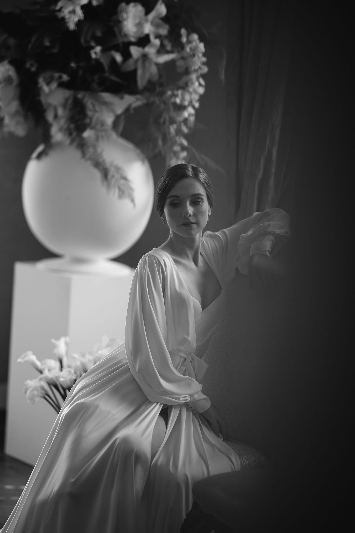 Black and white image showing the silhouette of a bride in a flowing white gown preparing for her wedding day.