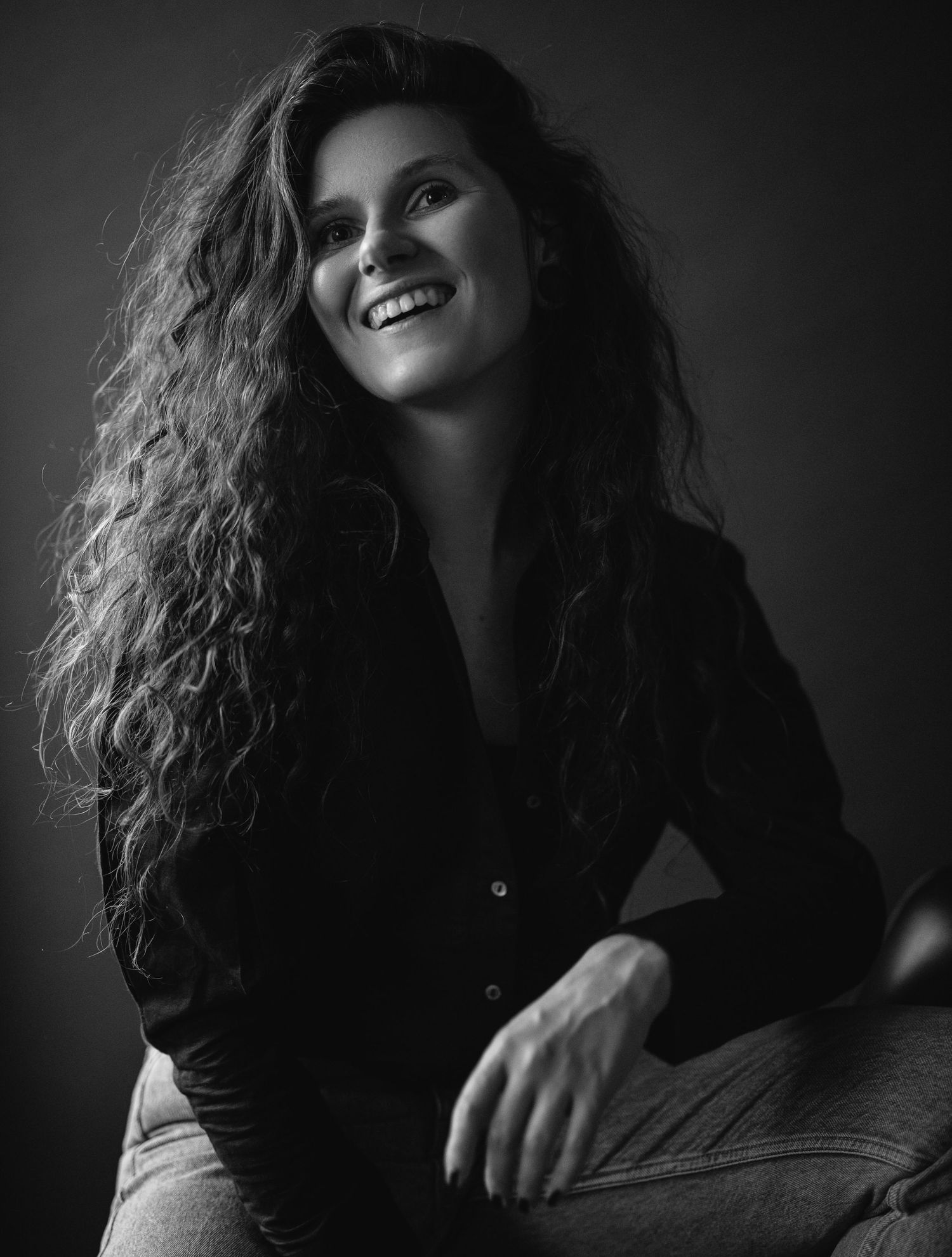 Black and white portrait featuring natural curly hair and genuine expression.