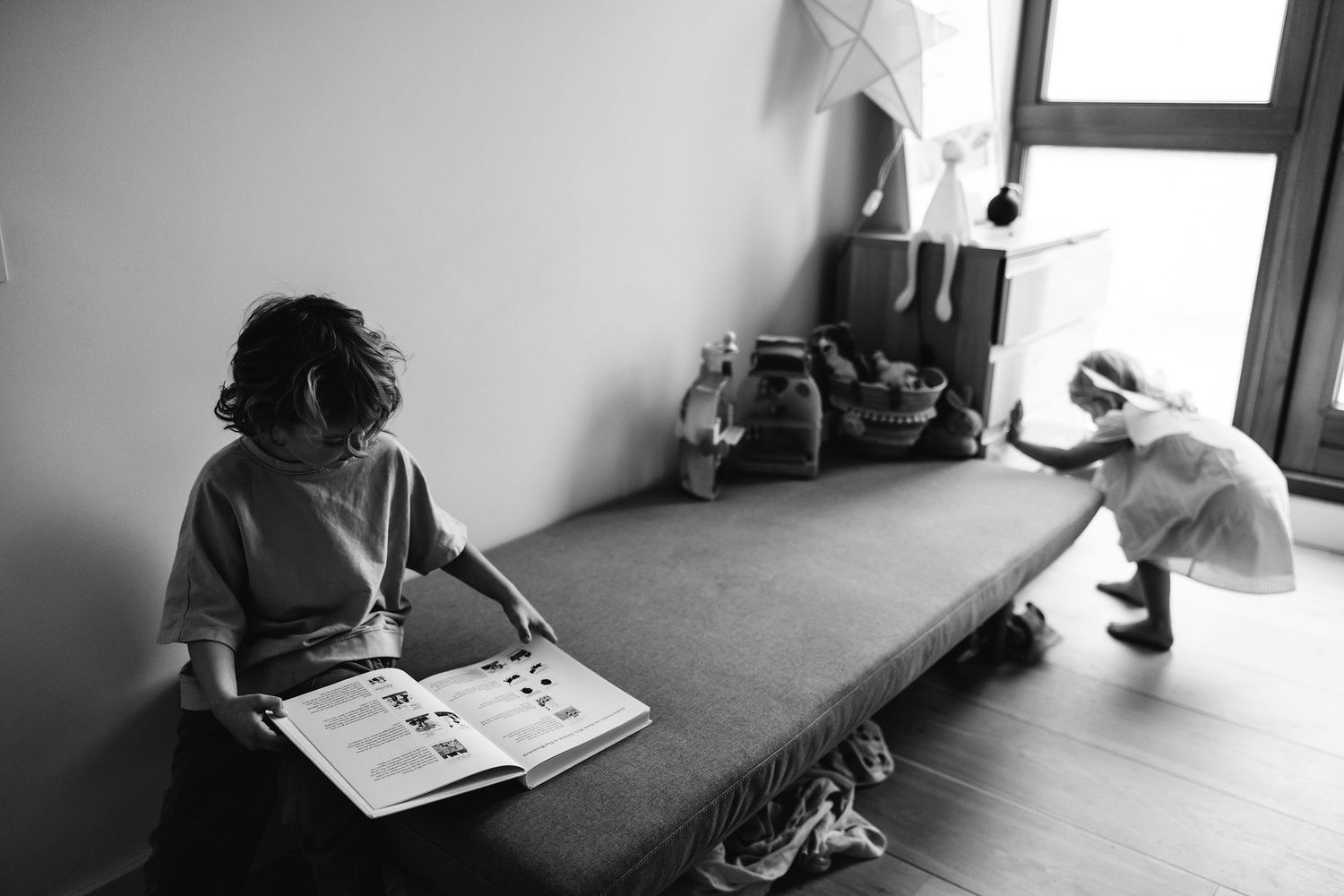 Black and white photos capturing quiet moments by a window in a modern interior.
