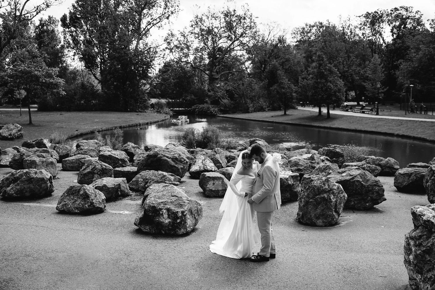 Wedding couple poses in outdoor garden setting with vintage cars in background.