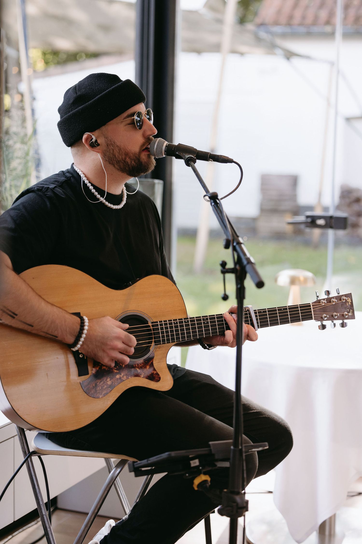 Musician in black attire performs with acoustic guitar at indoor venue.