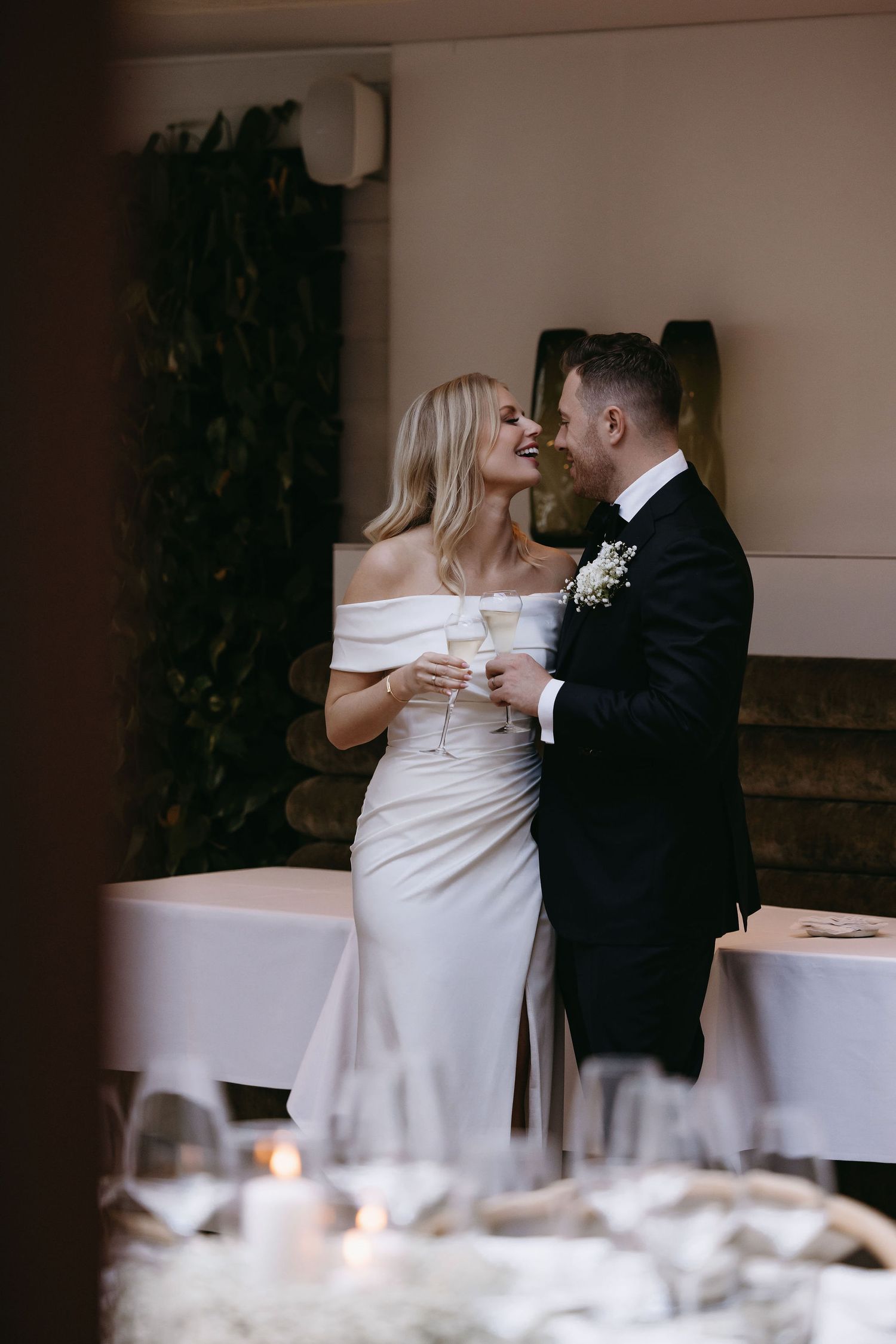 A romantic wedding moment as newlyweds share champagne and an intimate glance during their reception celebration.