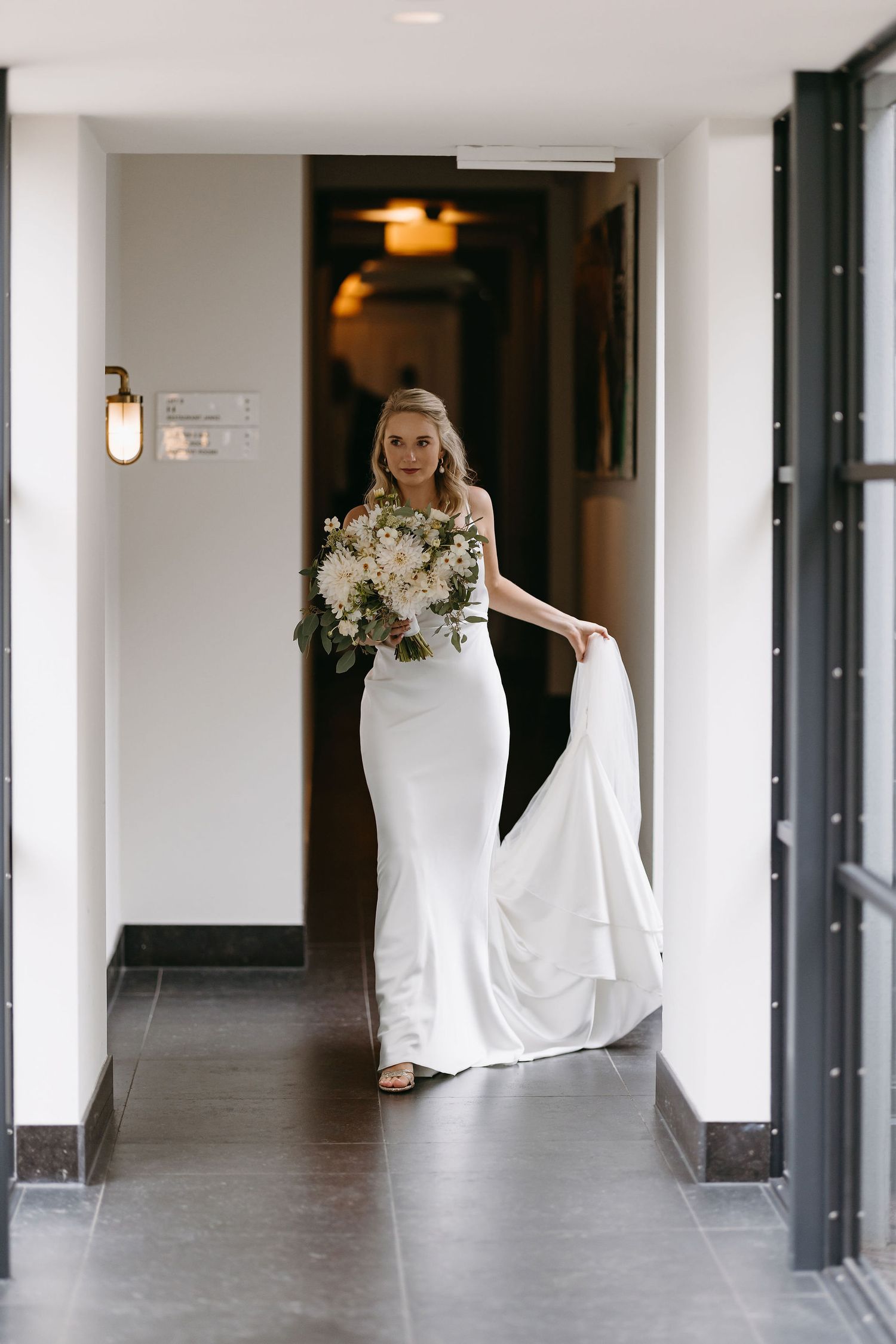 Bright modern hallway interior with white walls and floor-length mirror reflections.
