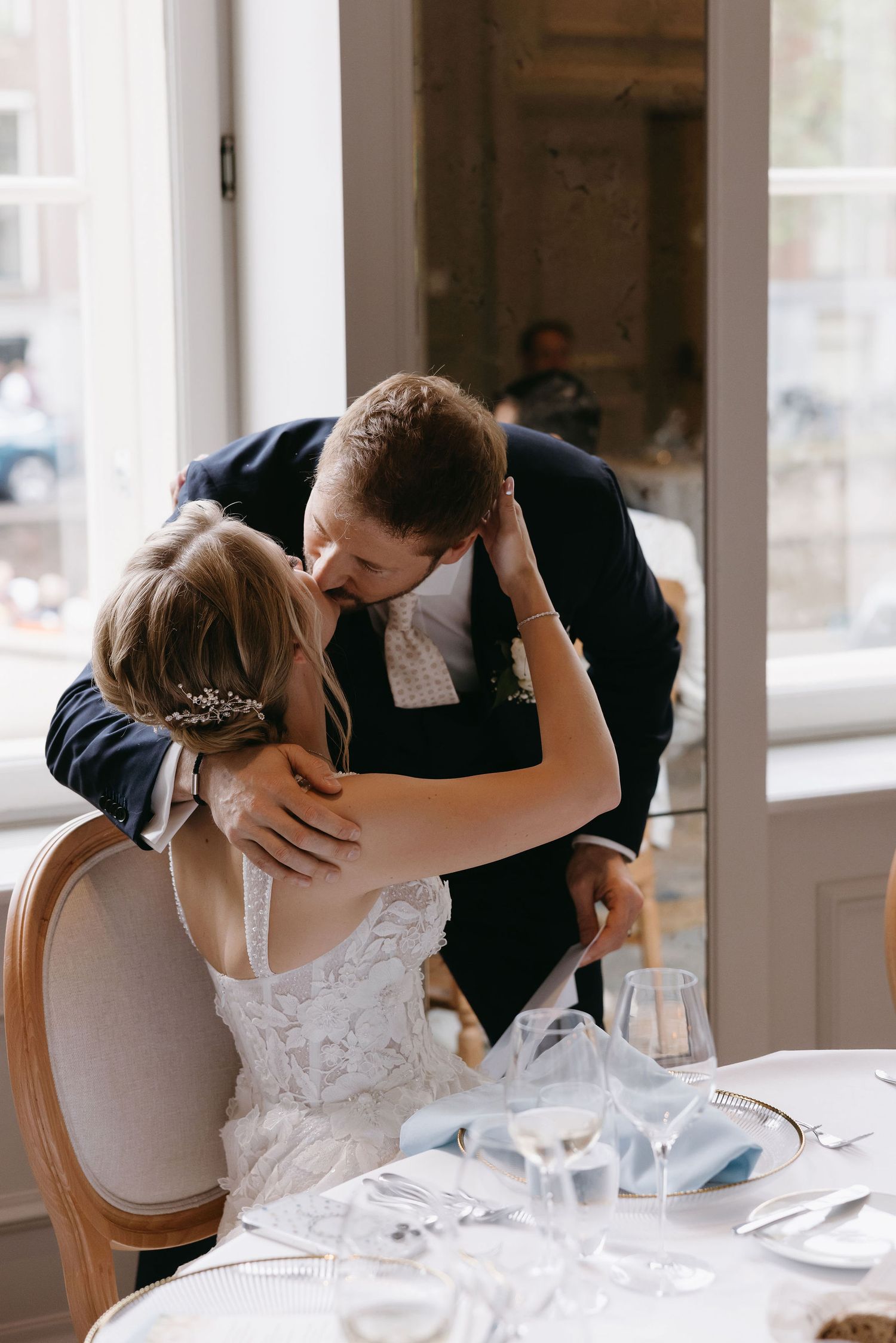 Romantic wedding couple sharing intimate moments at a dining table.
