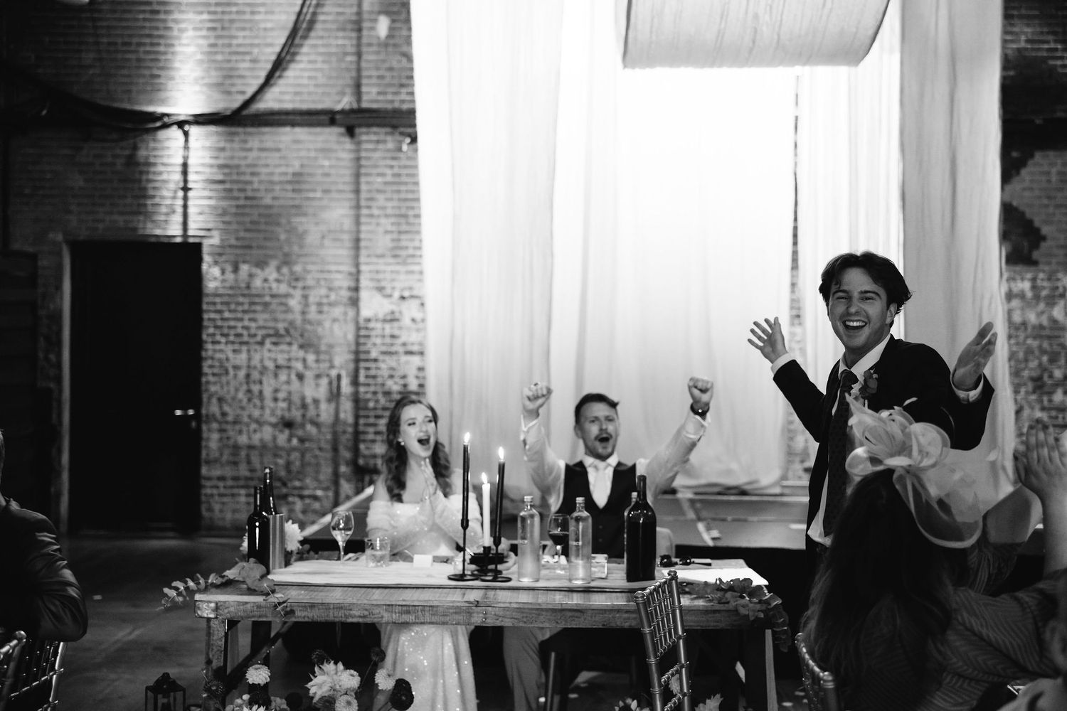 Wedding reception candid moments captured in black and white at an industrial venue.