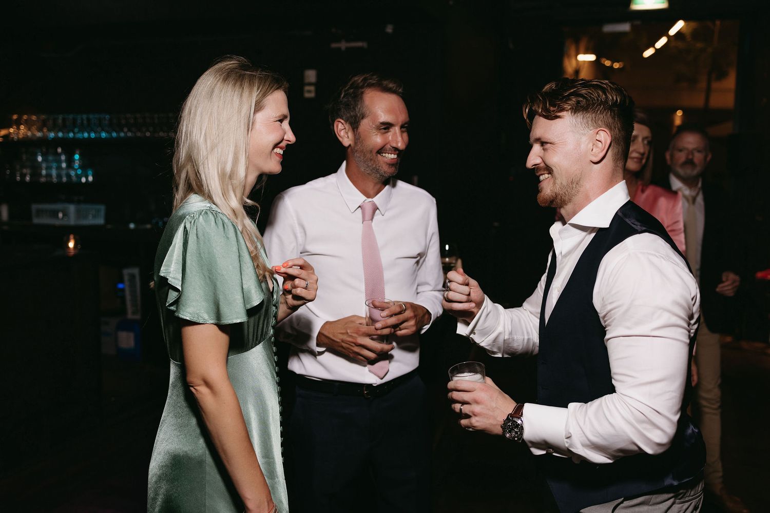 Wedding party enjoying drinks and conversation at an evening reception.