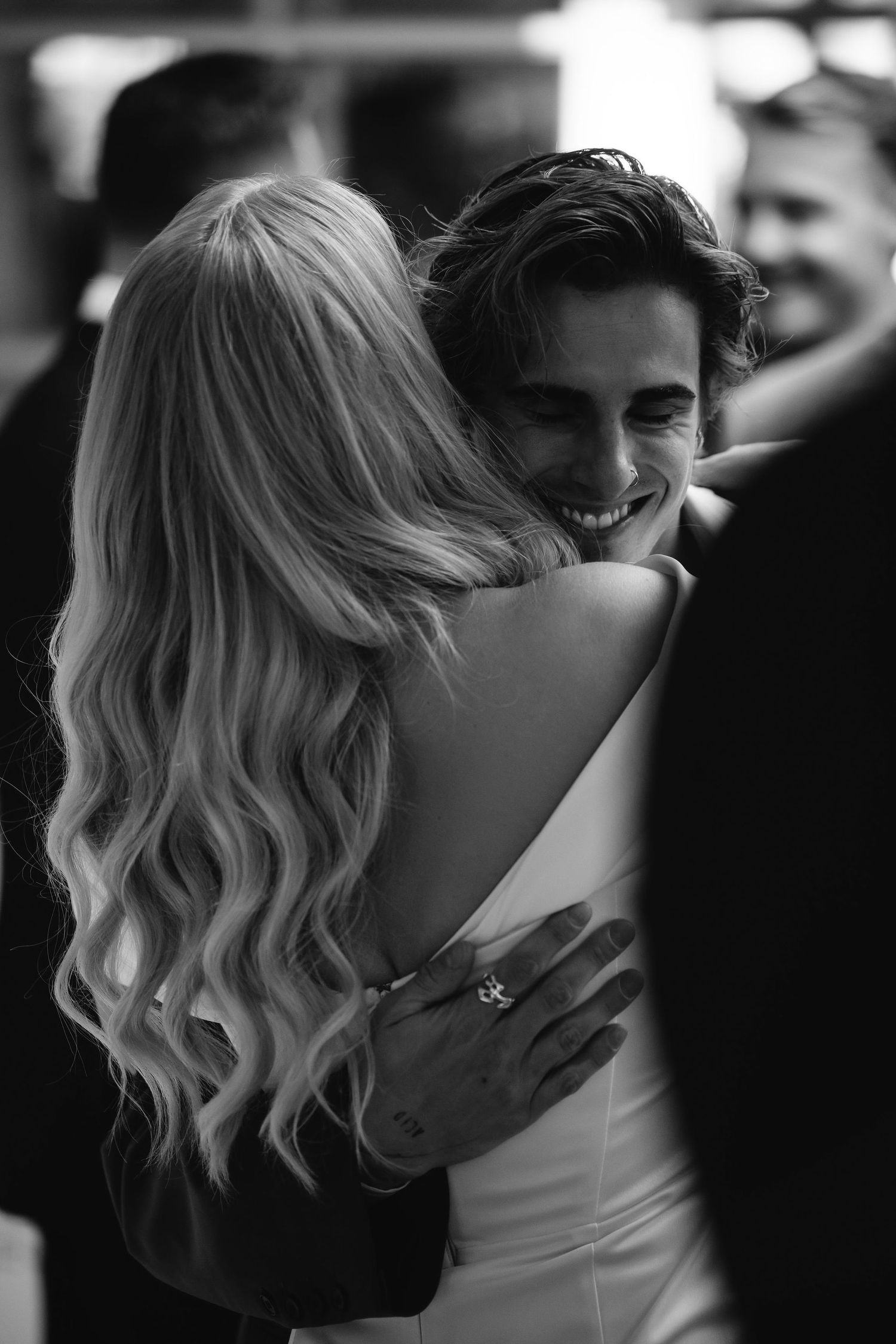 Black and white candid moment showing joyful embrace at wedding reception.