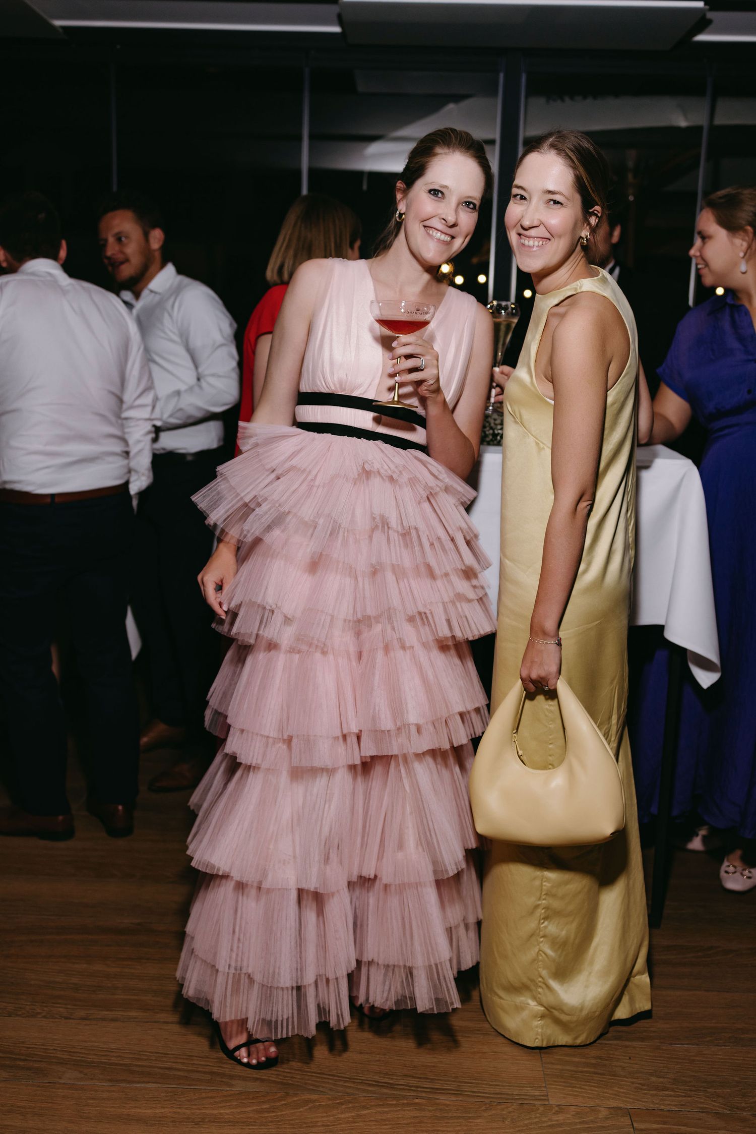 Wedding guests mingling on dance floor with pink tulle dress visible.