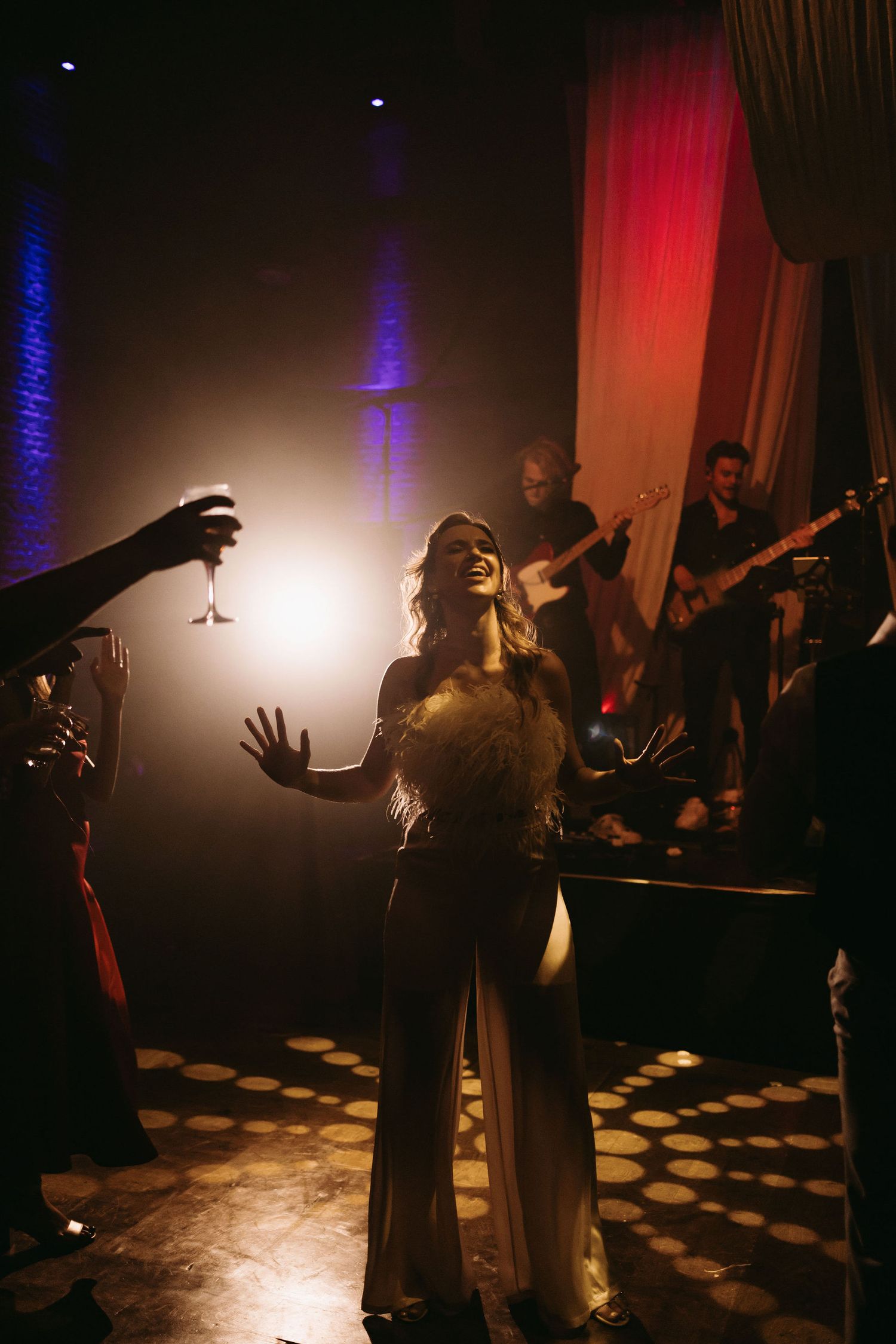 Dramatic dance performance in a dark room with red and blue lighting effects.