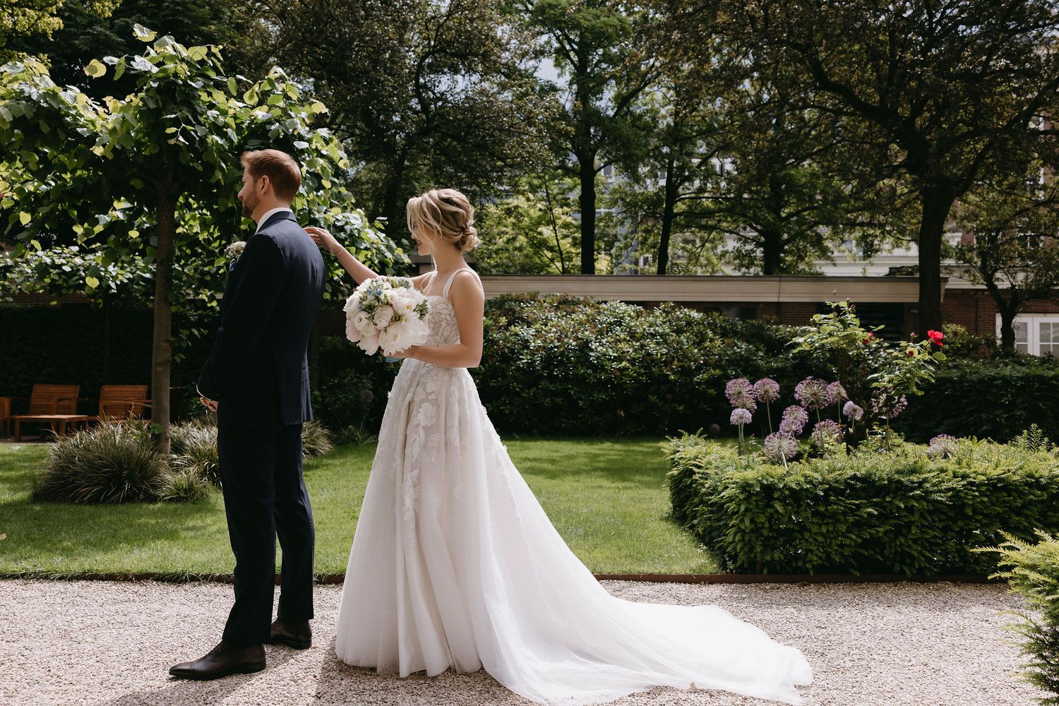 A couple shares tender moments while walking through a lush garden pathway.