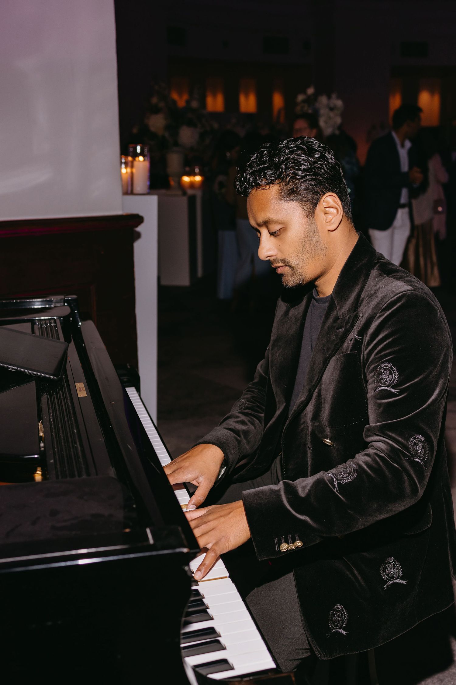 A pianist in a dark velvet jacket performs at a formal evening event.
