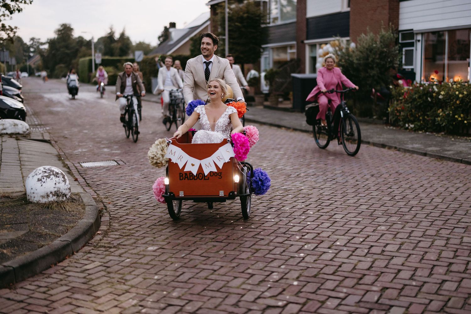 People walking and cycling on cobblestone streets of a charming neighborhood.