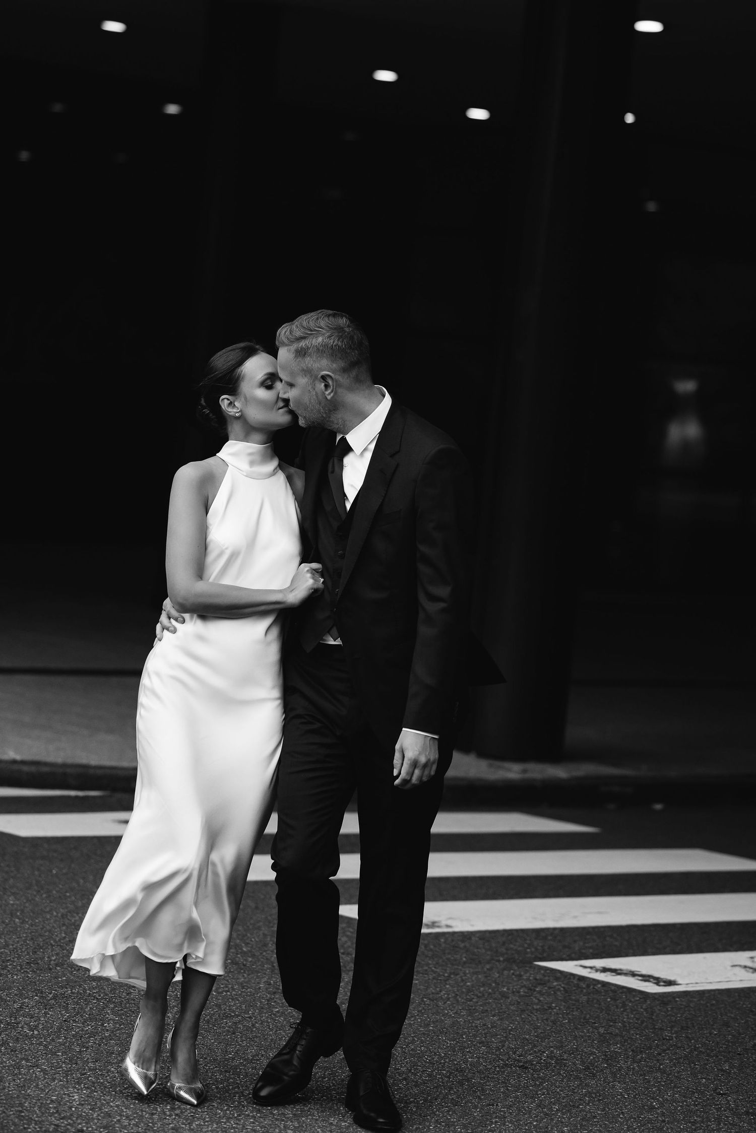 A black and white photo series showing a romantic couple sharing tender kisses in an elegant setting.