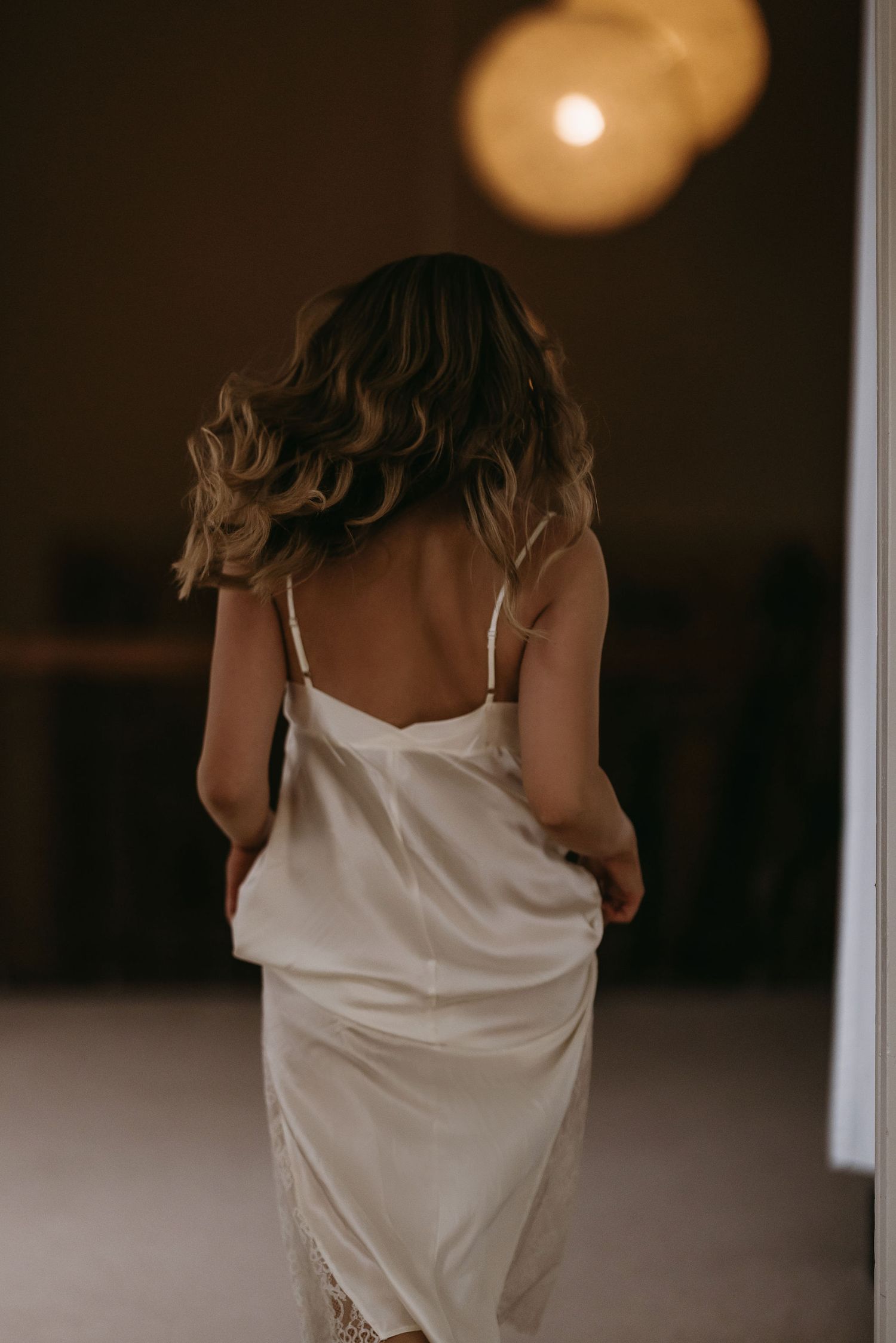 Artistic series showing a bride in a white dress in warm indoor lighting.
