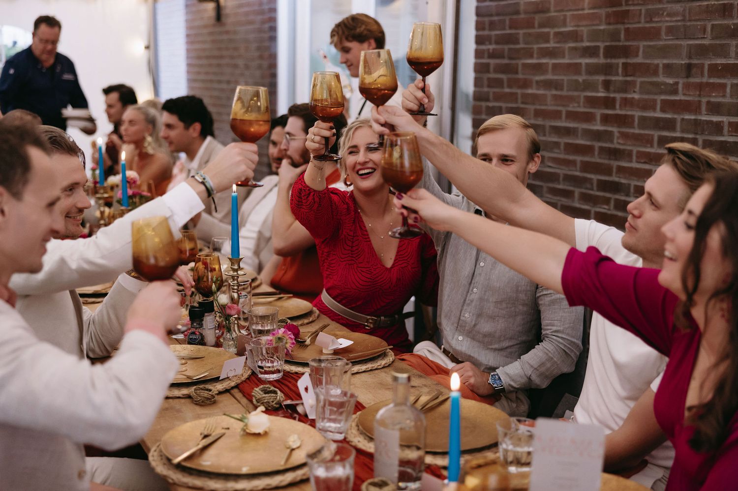 Celebration scene with guests toasting wine glasses across a decorated dining table.