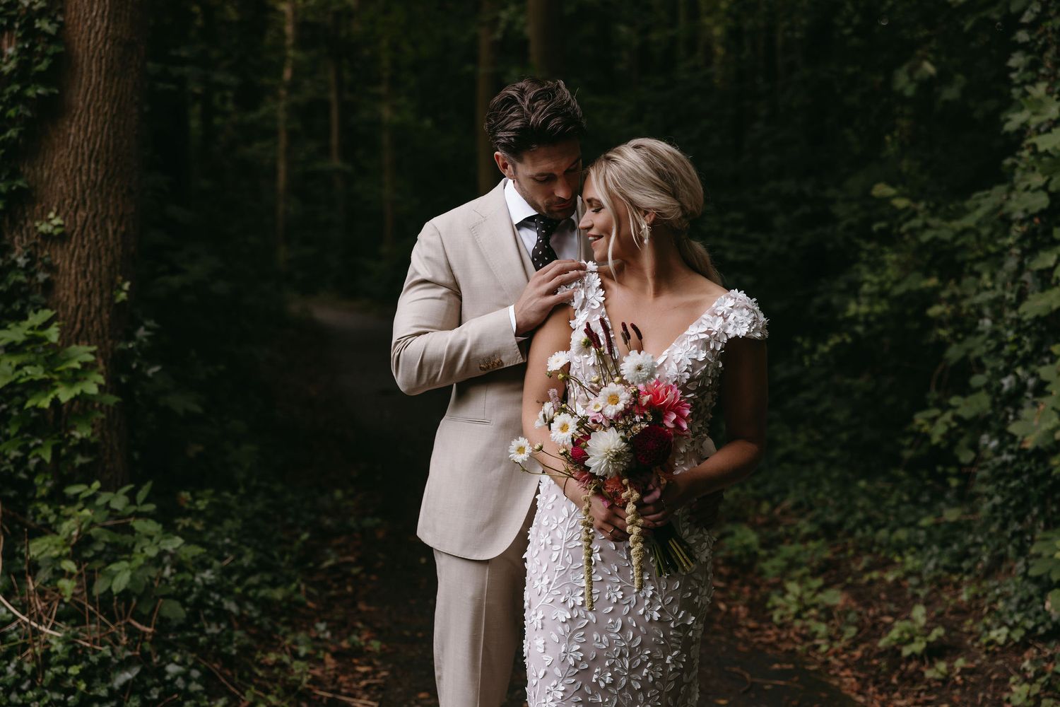 Romantic moment captured between wedding couple in a lush wooded setting.