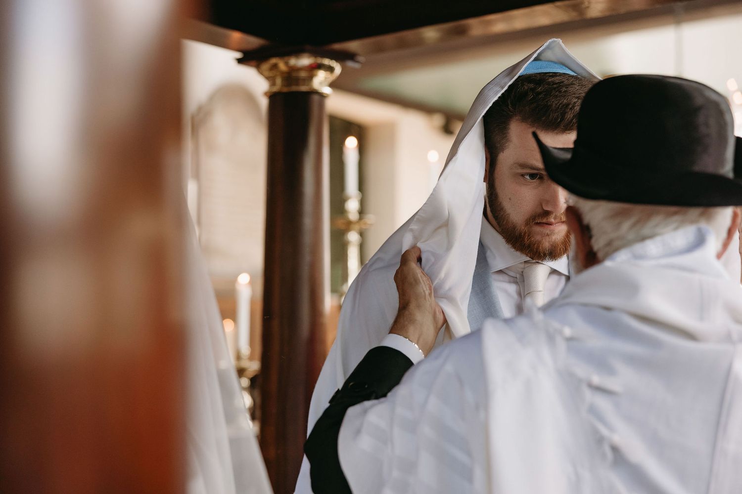 Intimate moment captured between two people in white ceremonial attire.
