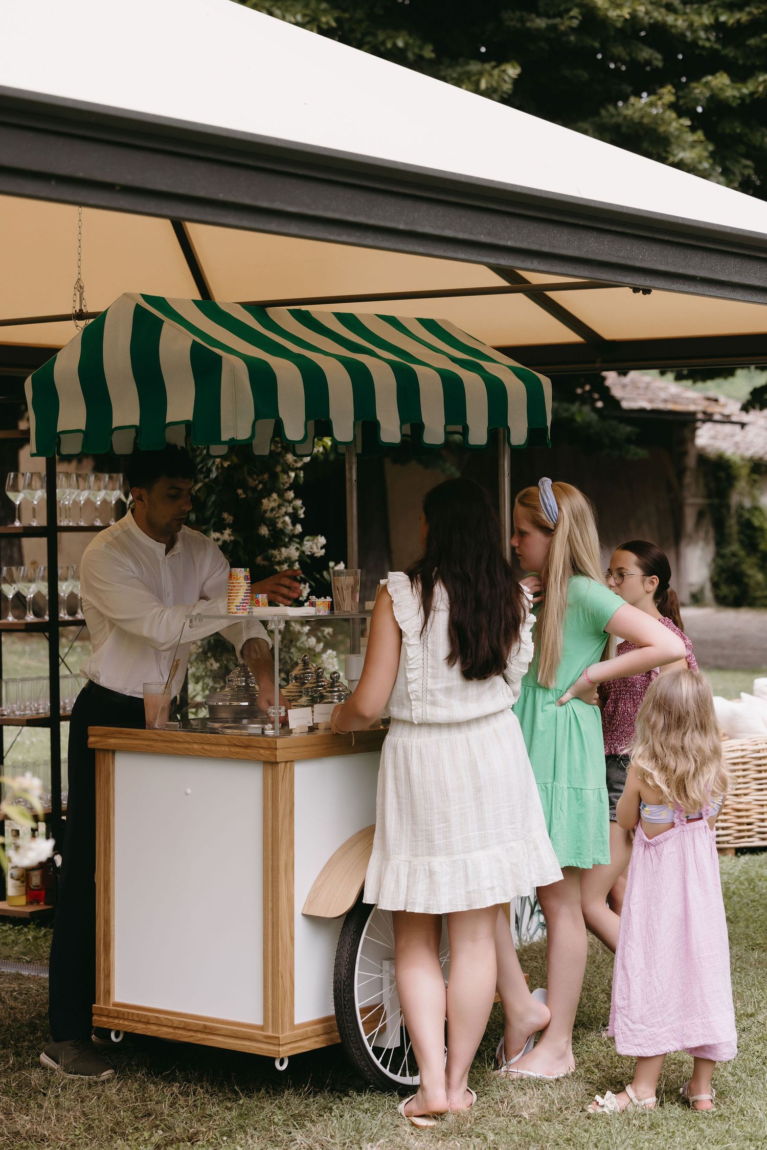 Vintage-style cart with green striped awning serving refreshments at an outdoor event.