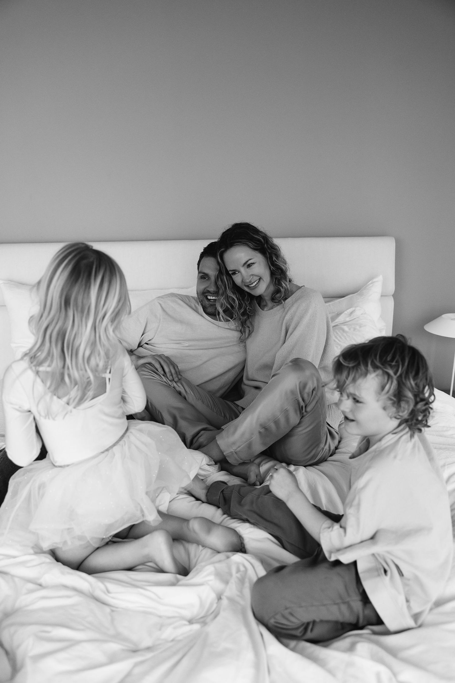 Family enjoying a relaxed morning together on white bedding.