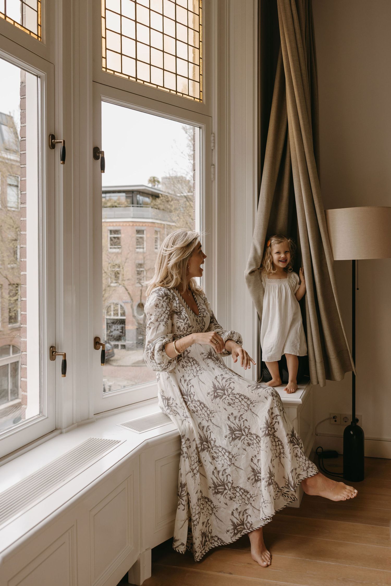 Intimate family moment by large window with city view.