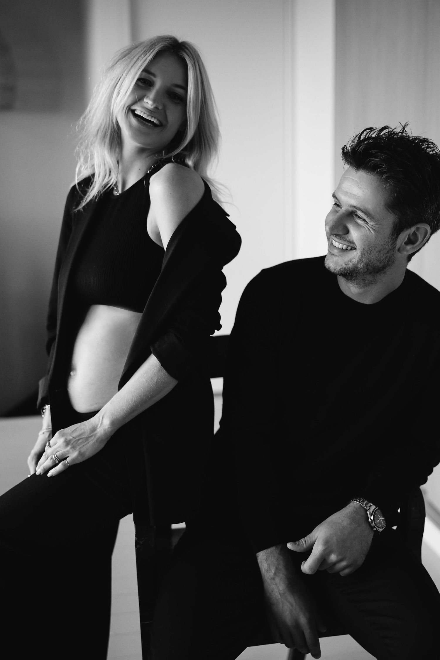 Candid black and white photo of couple sharing joyful laughter during maternity shoot.