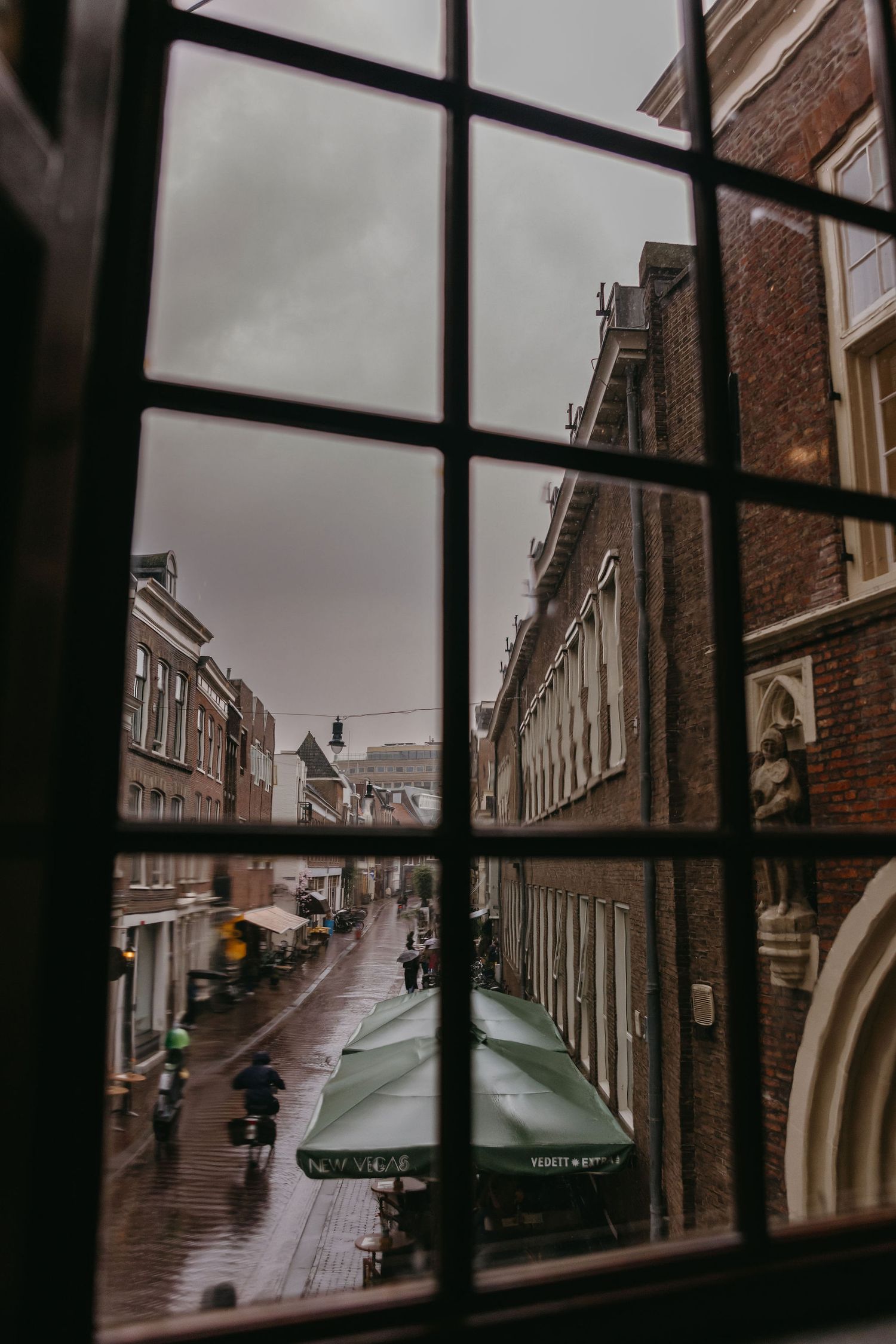 Rainy city street view through a window pane showing historic brick buildings.
