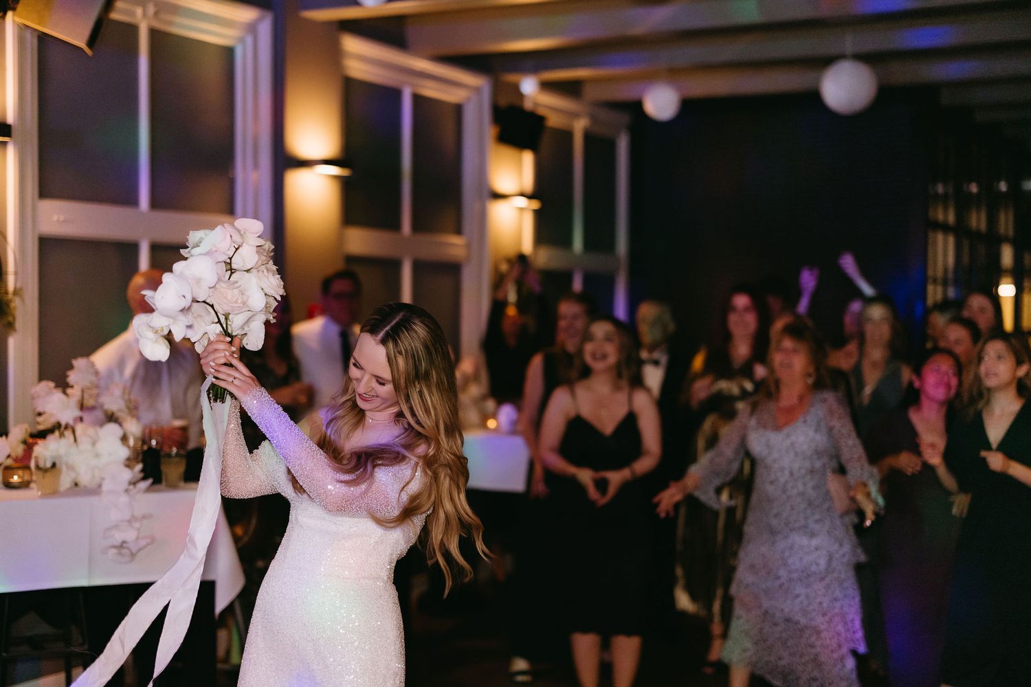 Party guests dancing and celebrating at a dimly lit evening reception.