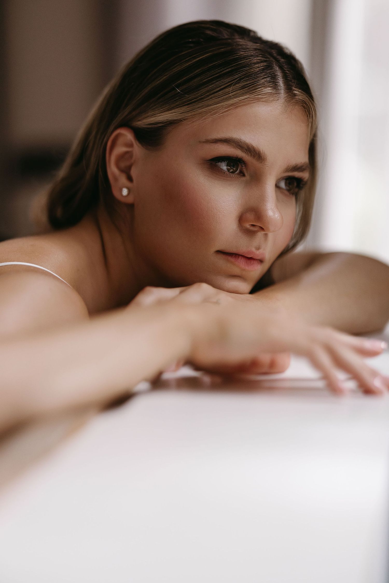 Close-up boudoir portrait in soft natural light showing gentle facial features and elegant makeup.