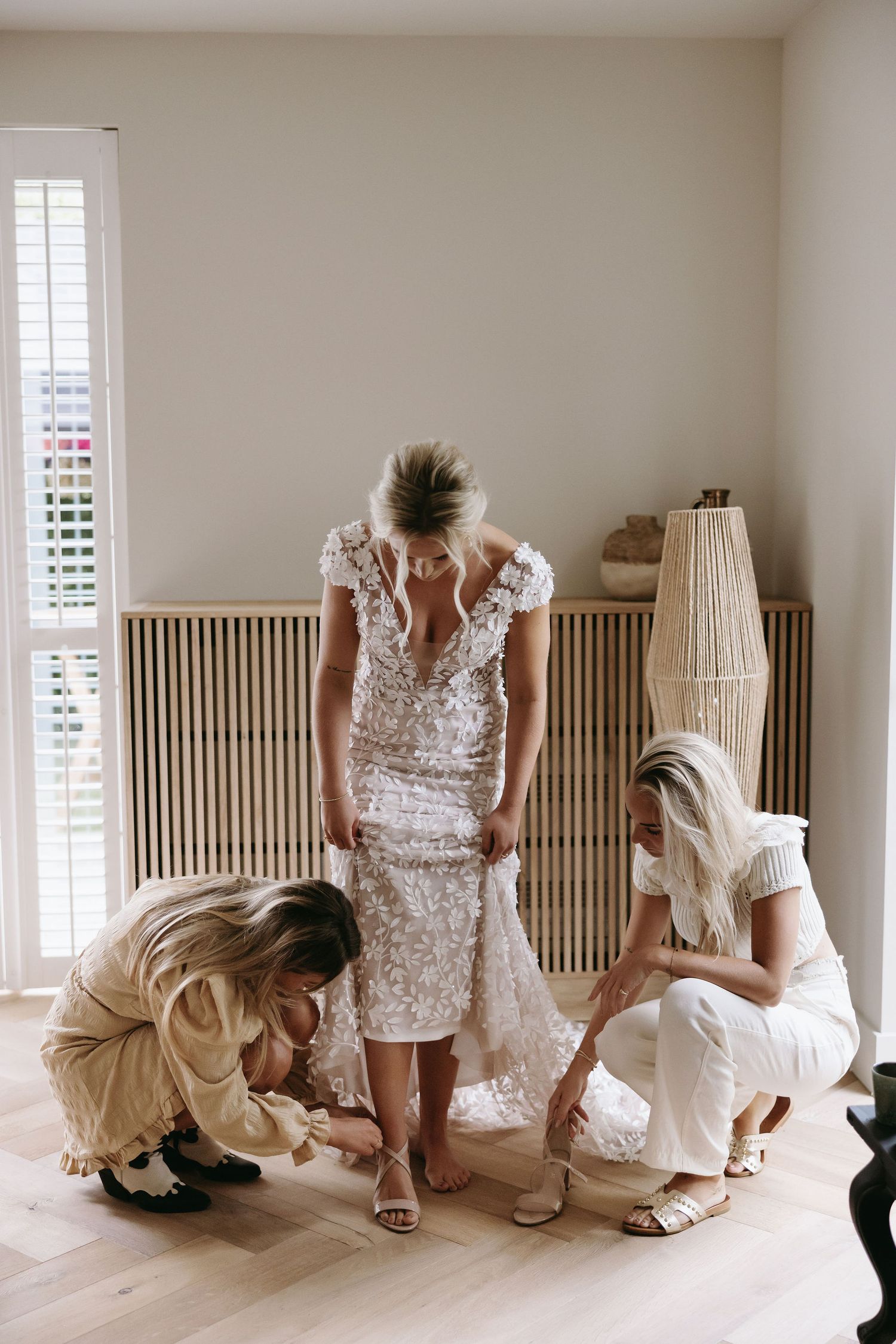 Getting ready scene in a bright white room with wooden shutters and natural light.