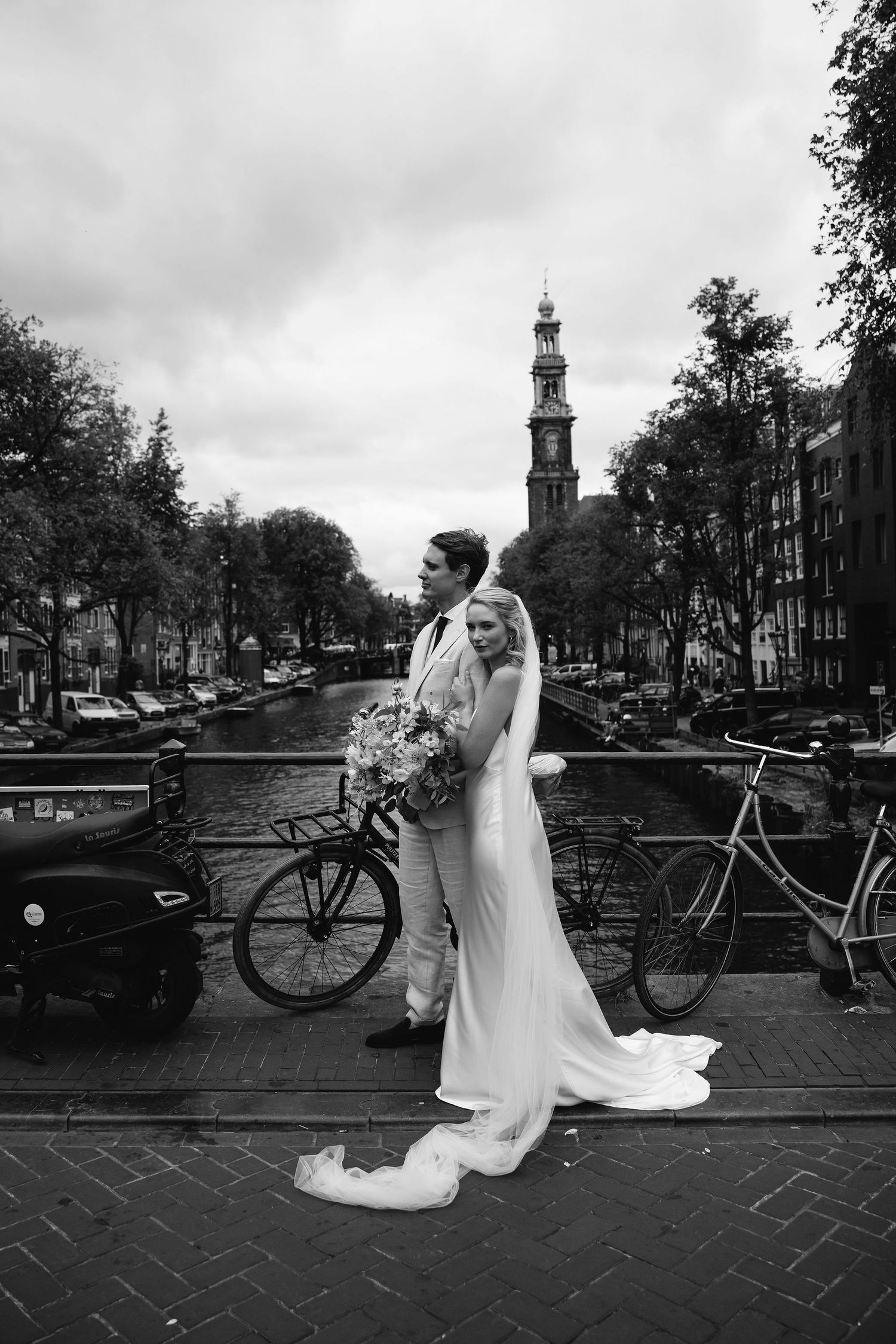 Black and white photos of newlyweds posing by Amsterdam canals with bicycles and bridges in the background.