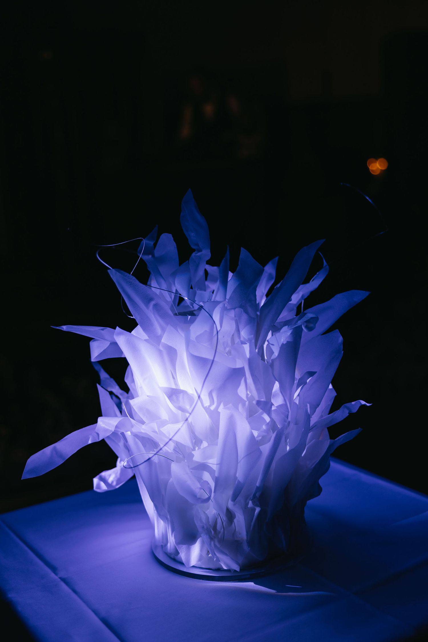 Illuminated blue ice sculpture glowing dramatically against dark background at event.