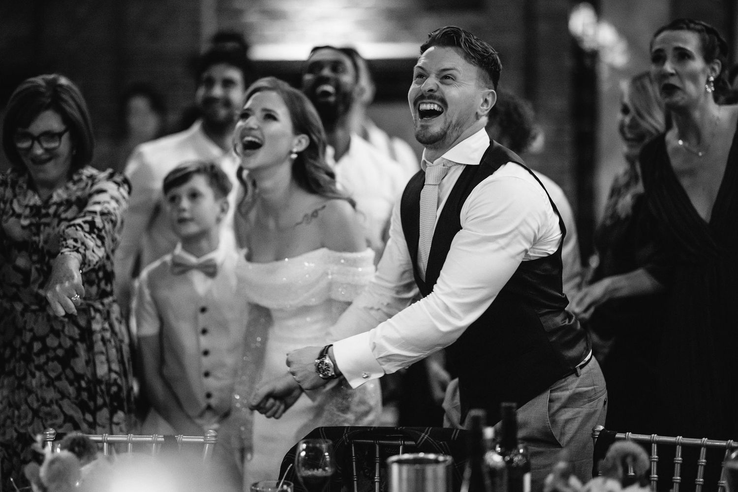 Wedding reception party scene with joyful dancing and laughter in dramatic black and white.