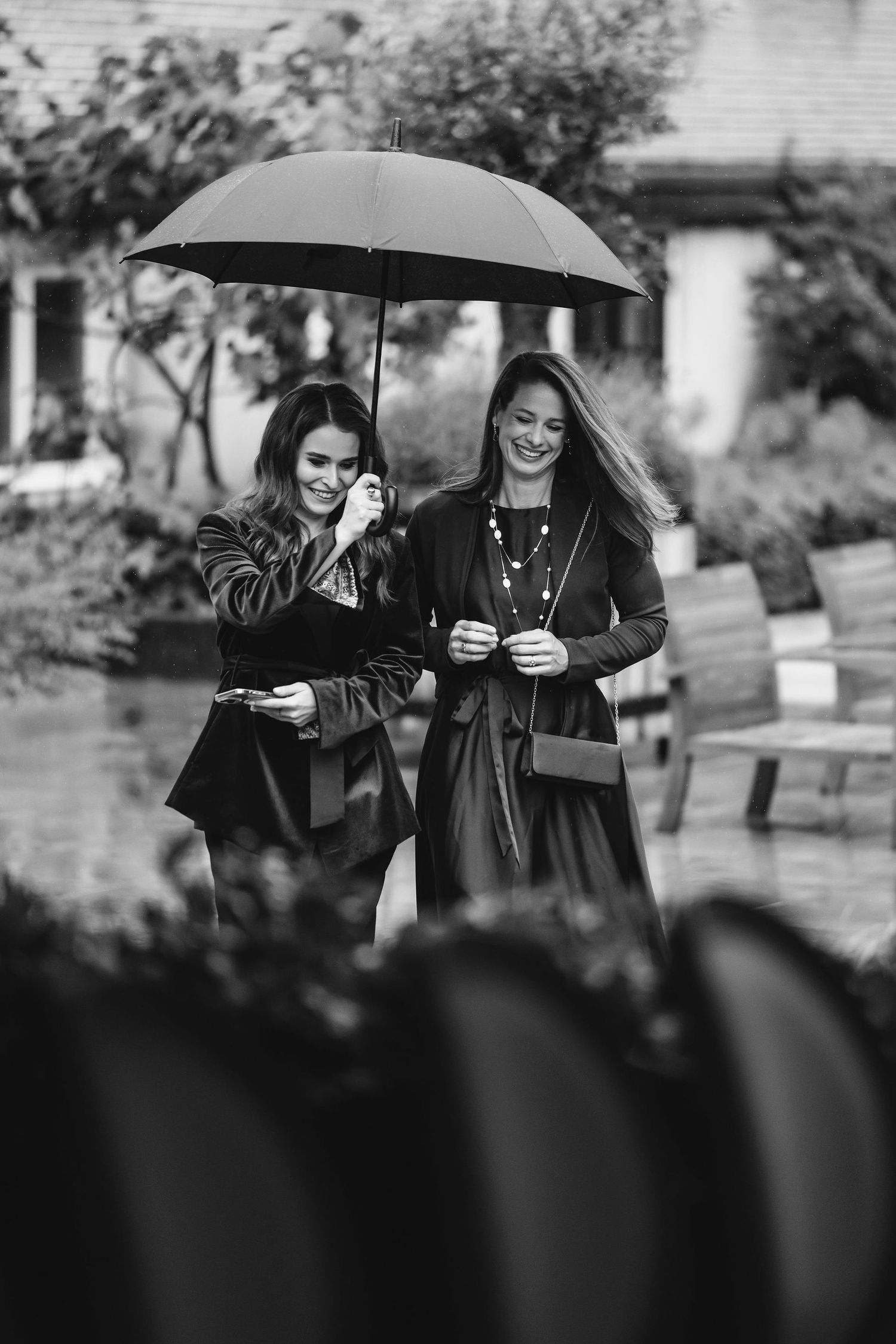 Black and white photo of people sharing umbrellas in the rain.