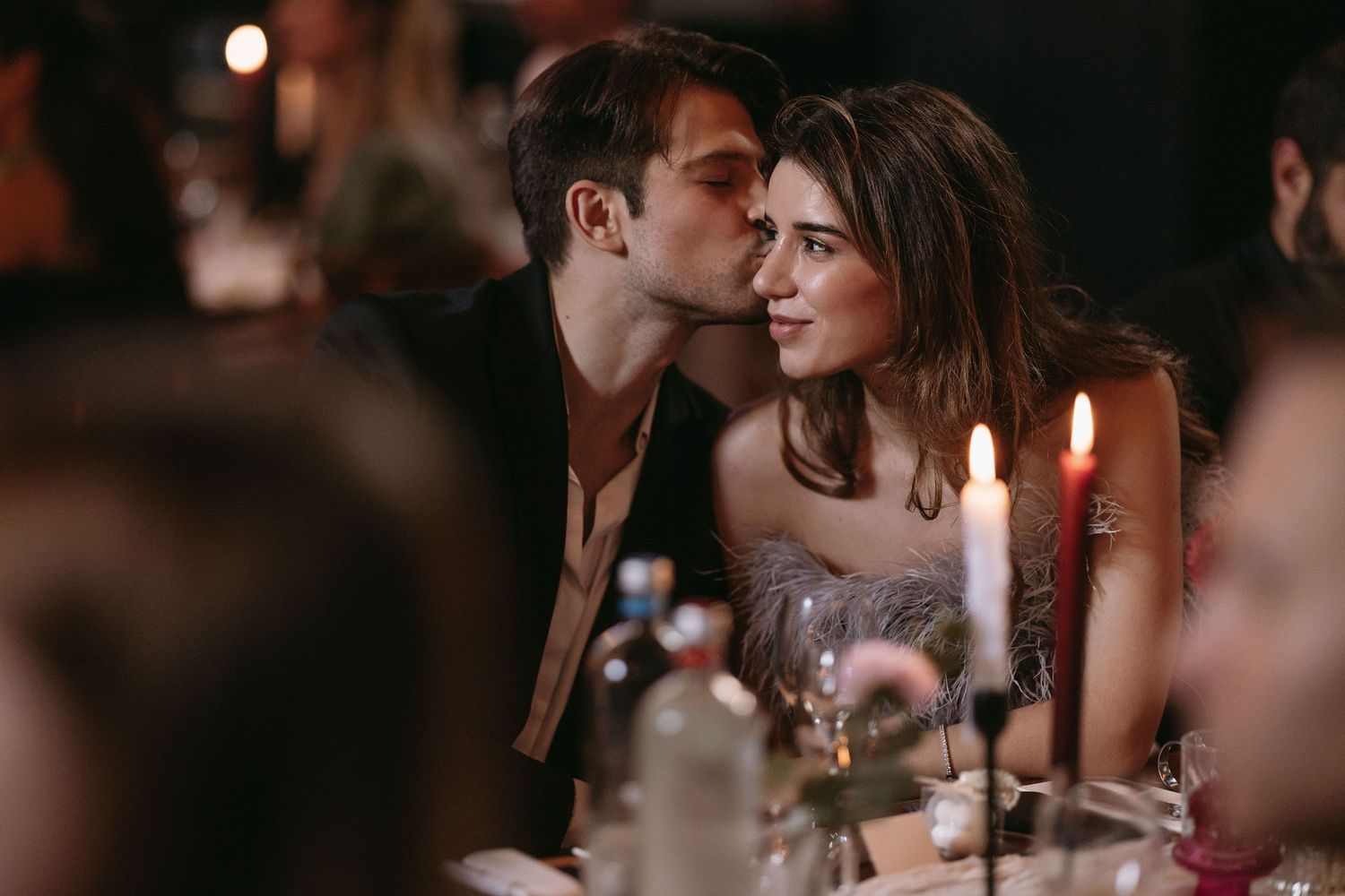 Romantic candlelit dinner scene with couple sharing intimate moment.