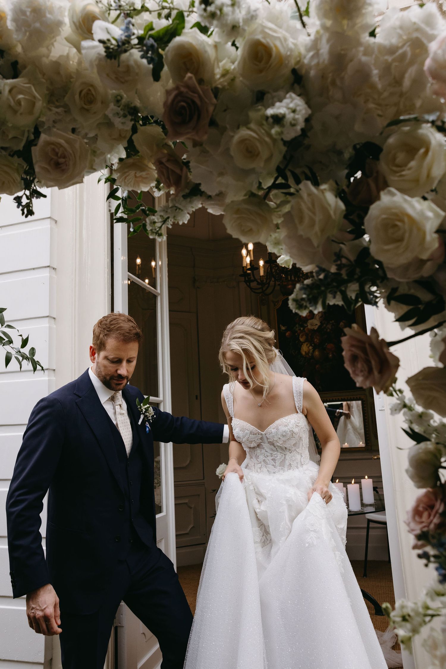 Couple sharing a romantic dance moment under white floral decorations and elegant lighting.