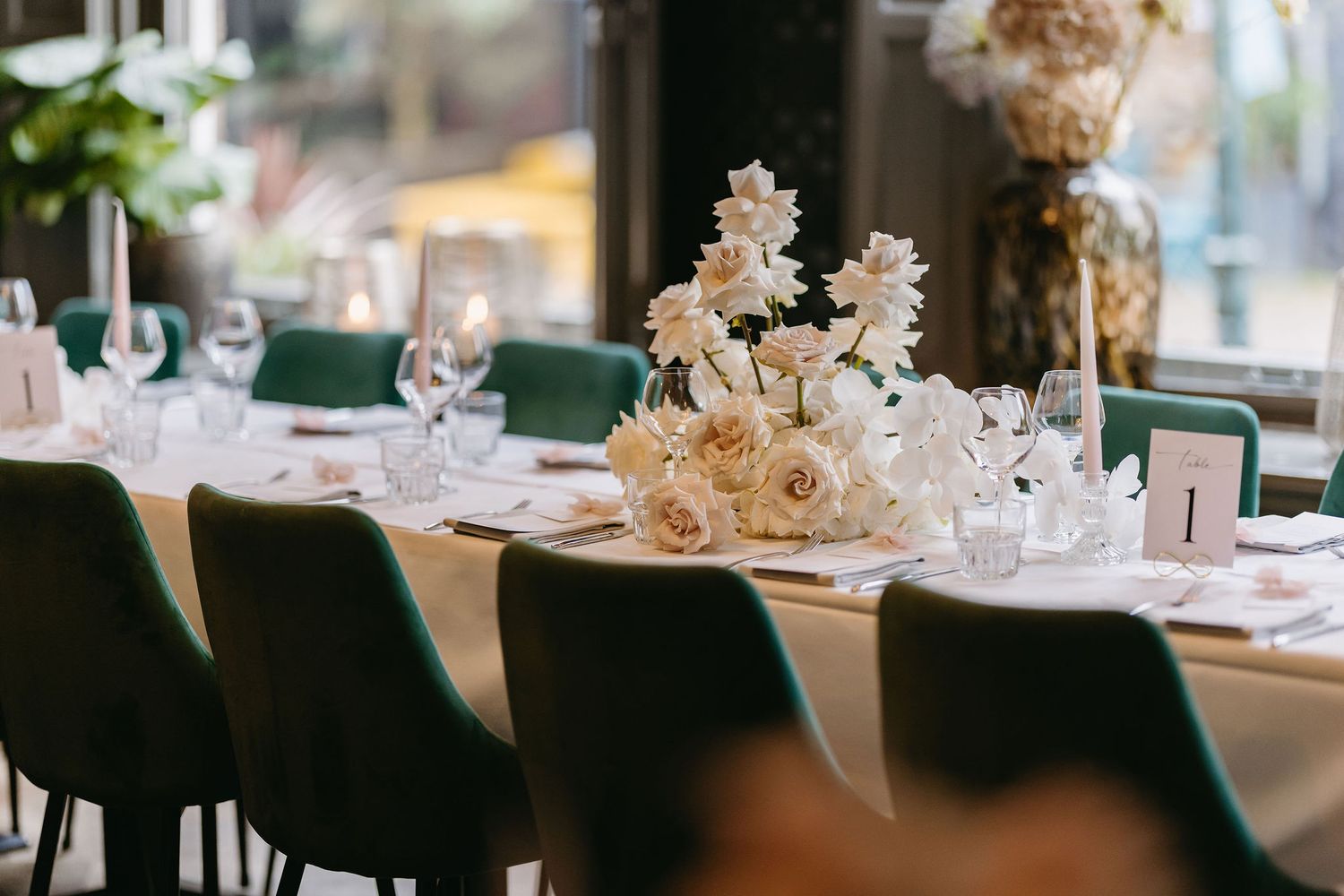 Modern reception table setting with elegant white decor and place settings at a wedding venue.