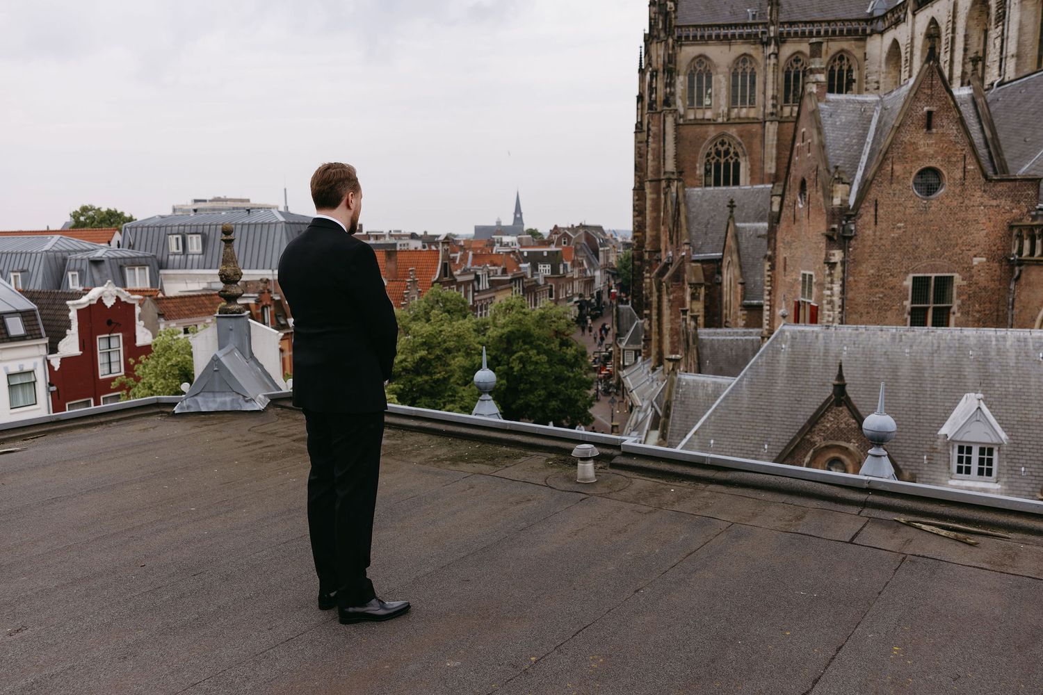 Couple observes city rooftops from elevated viewpoint.