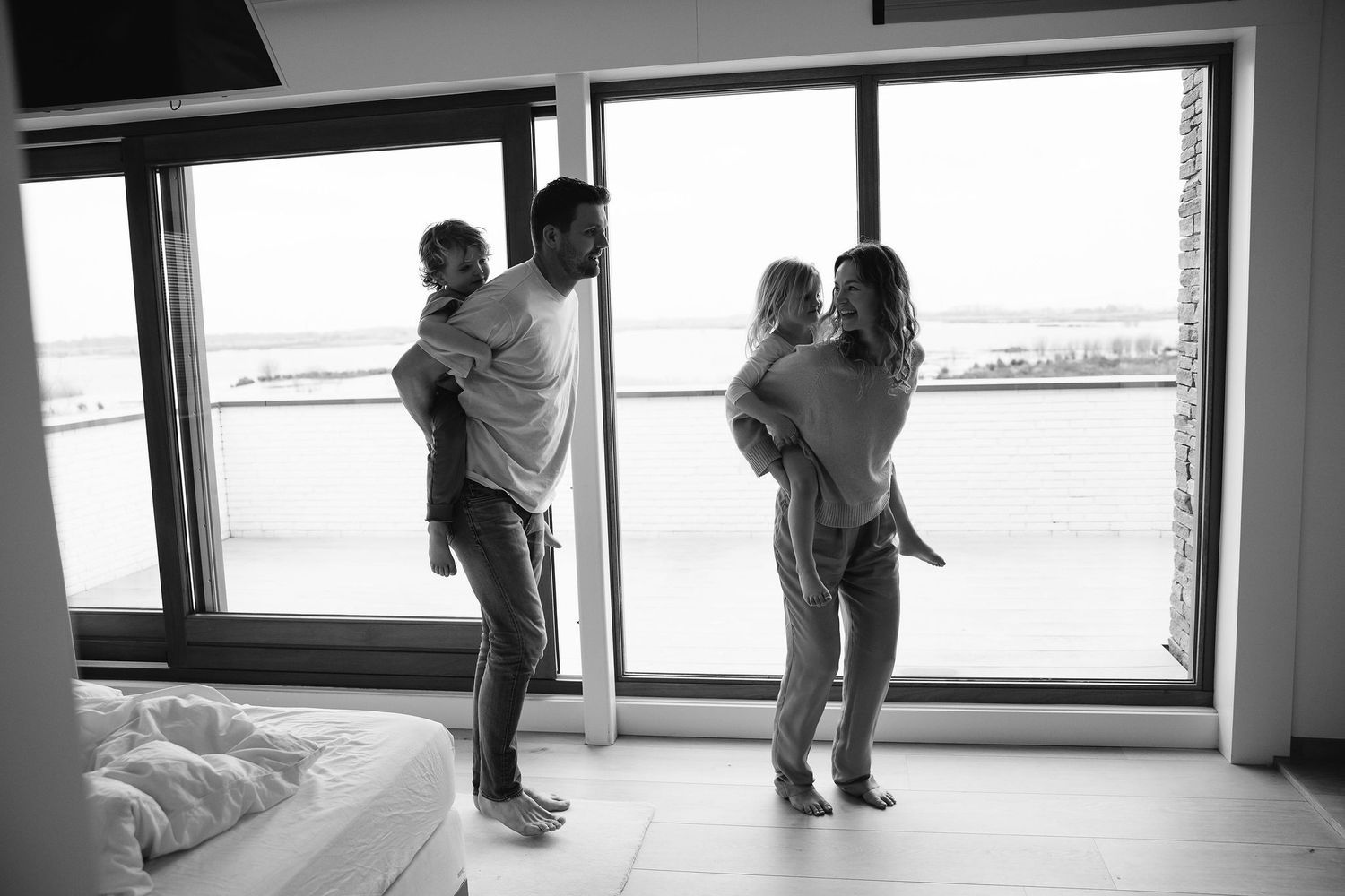 Silhouettes of people standing by large windows in an empty room.