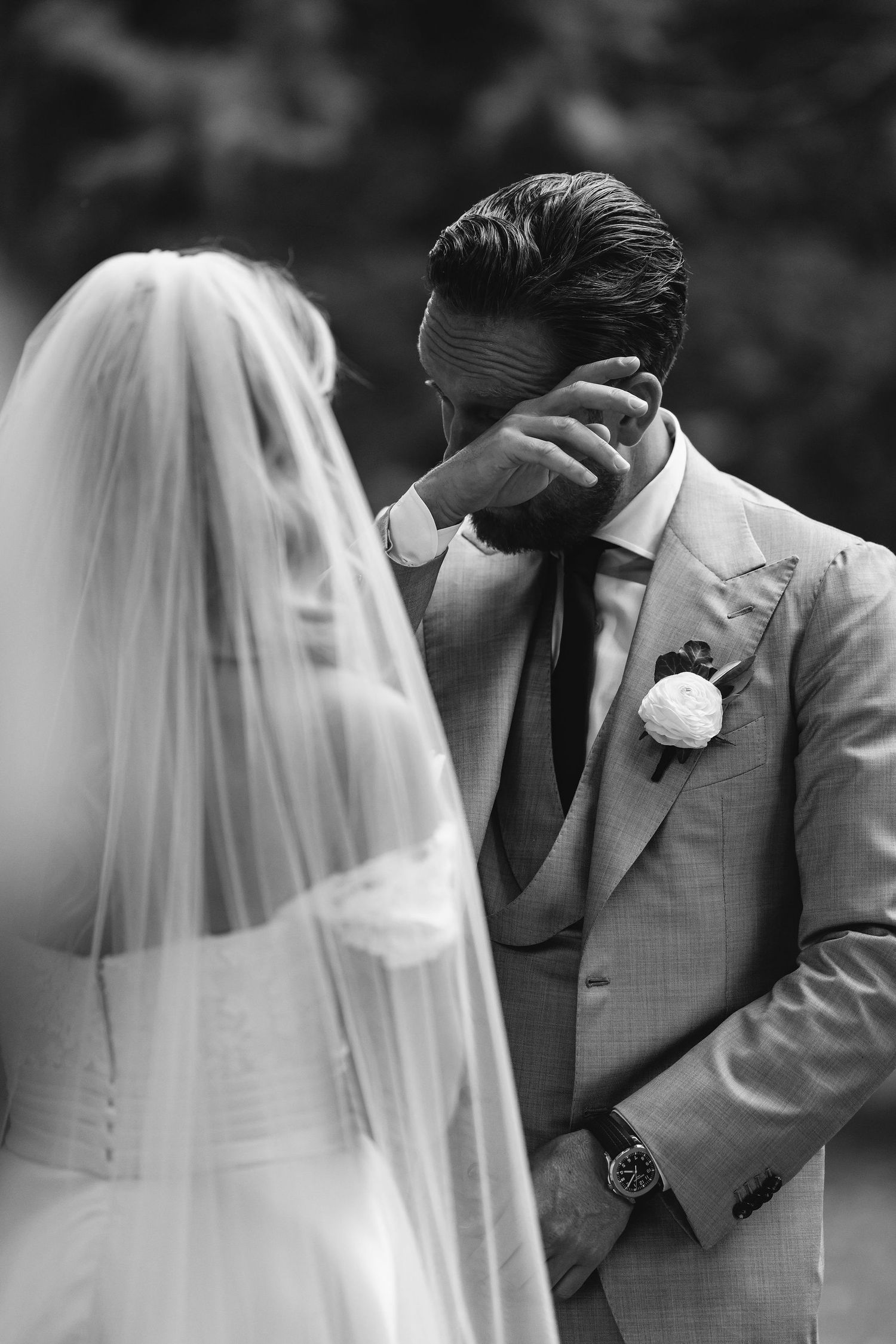 An emotional wedding moment captured in black and white with a veiled bride.