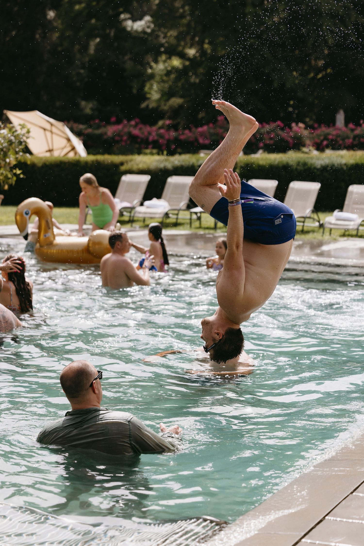 Someone performing an acrobatic flip into a swimming pool during a wedding celebration.