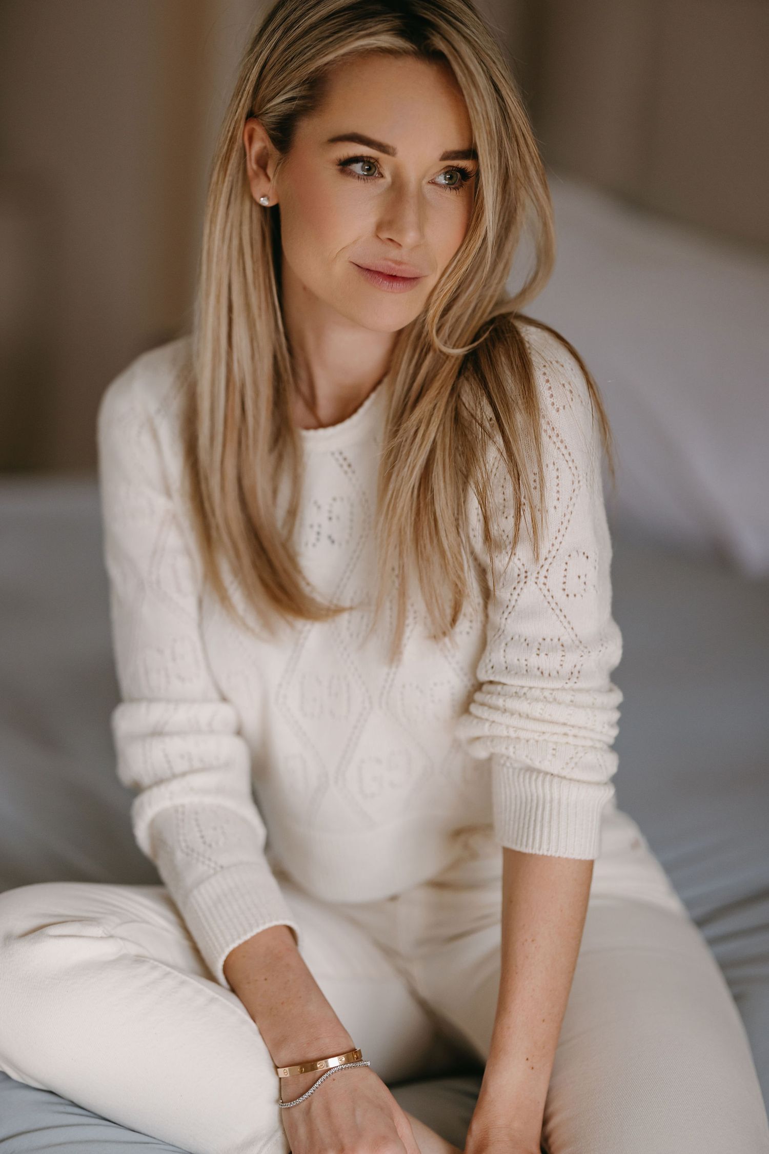 Lifestyle portrait of someone wearing a cozy white knit sweater while relaxing at home.